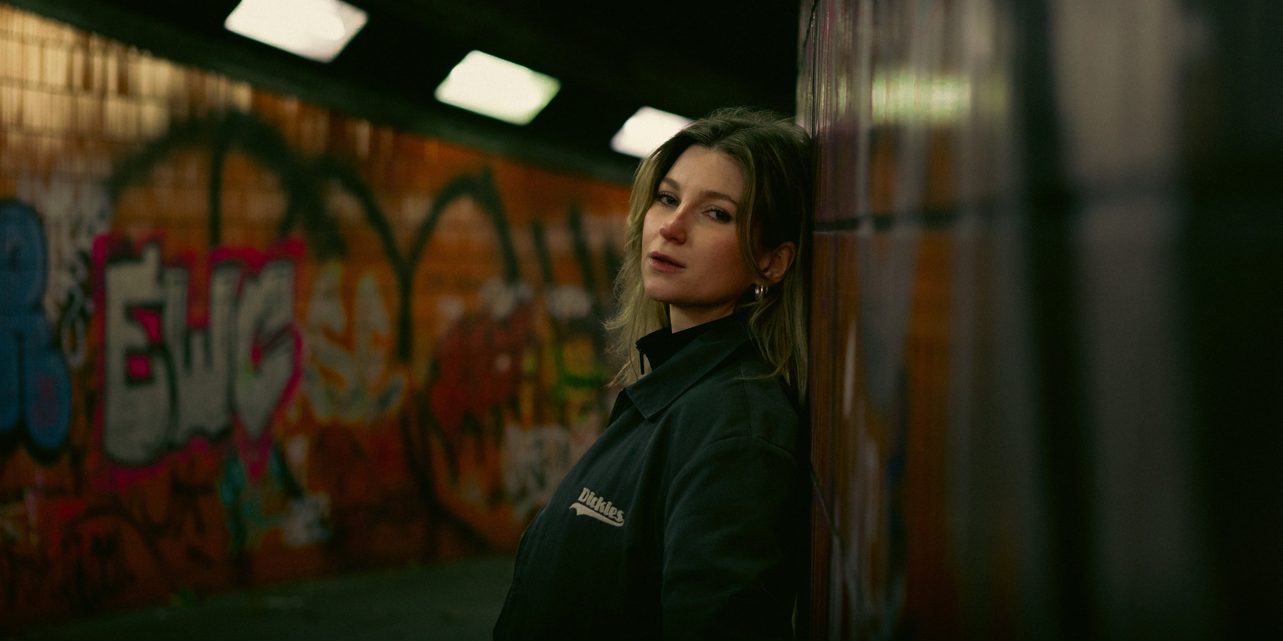 Female portrait against a graffiti-covered wall in a Berlin urban underpass