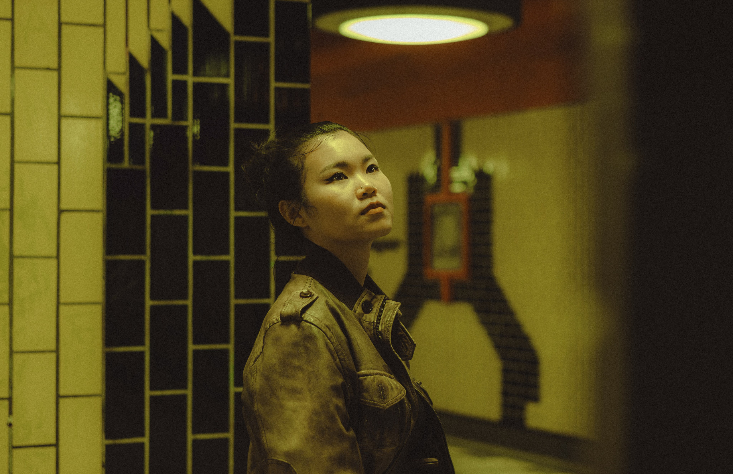 Woman looking upward beside a tiled wall at a Berlin U-Bahn station