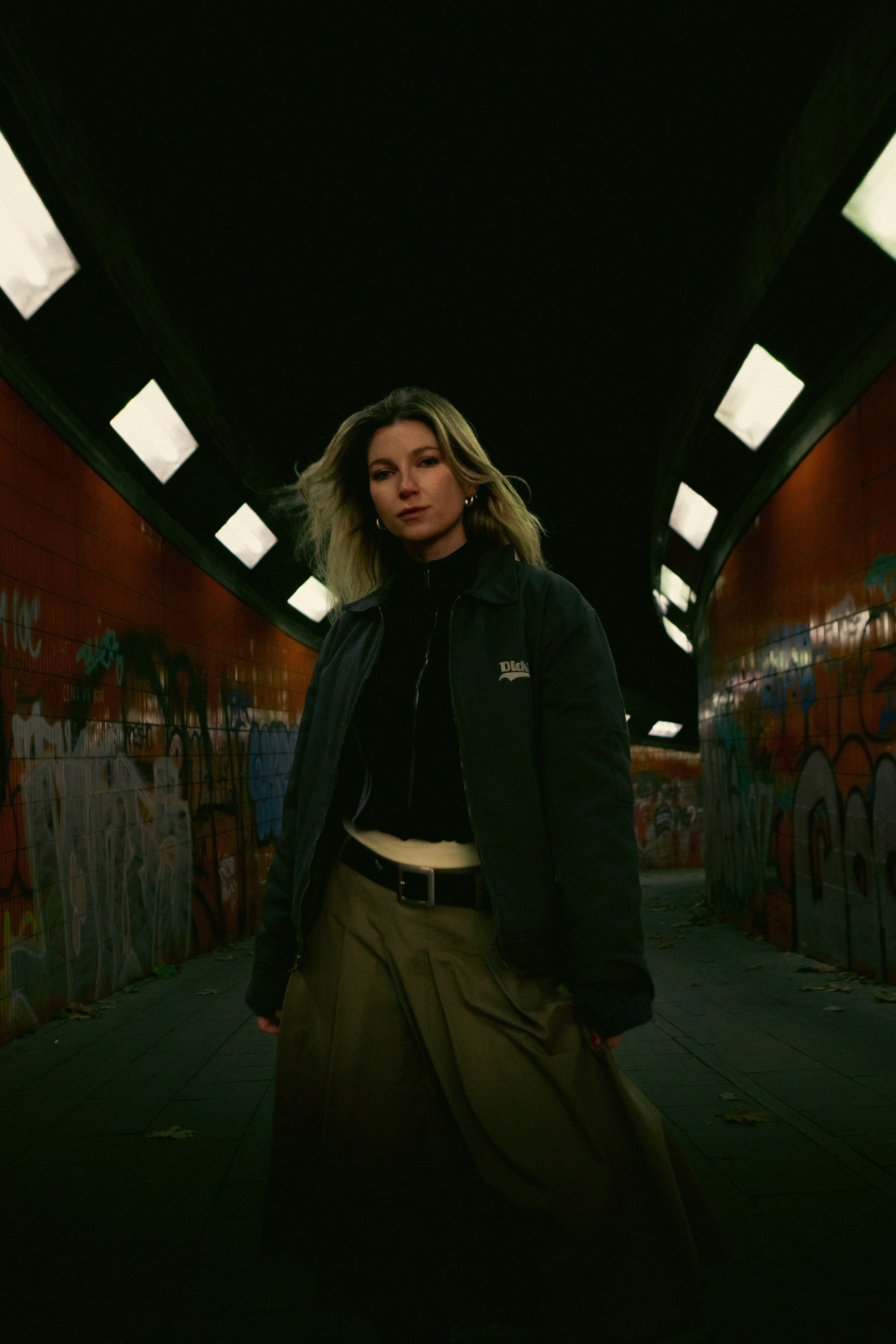 Cinematic female portrait in a Berlin urban underpass with graffiti walls and dramatic lighting