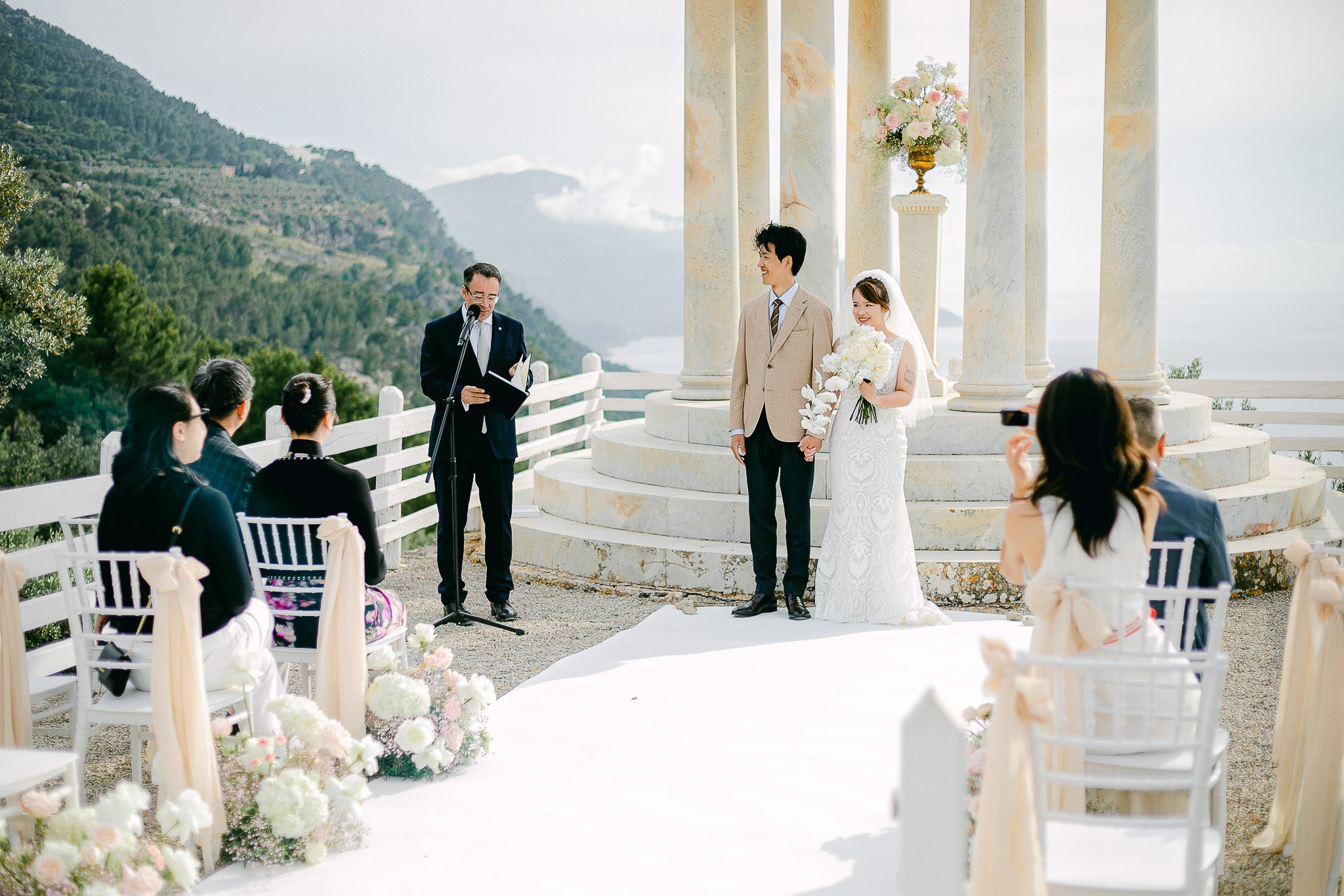 Bride and groom at the Son Marroig temple with guests seated for their exclusive Mallorca elopement