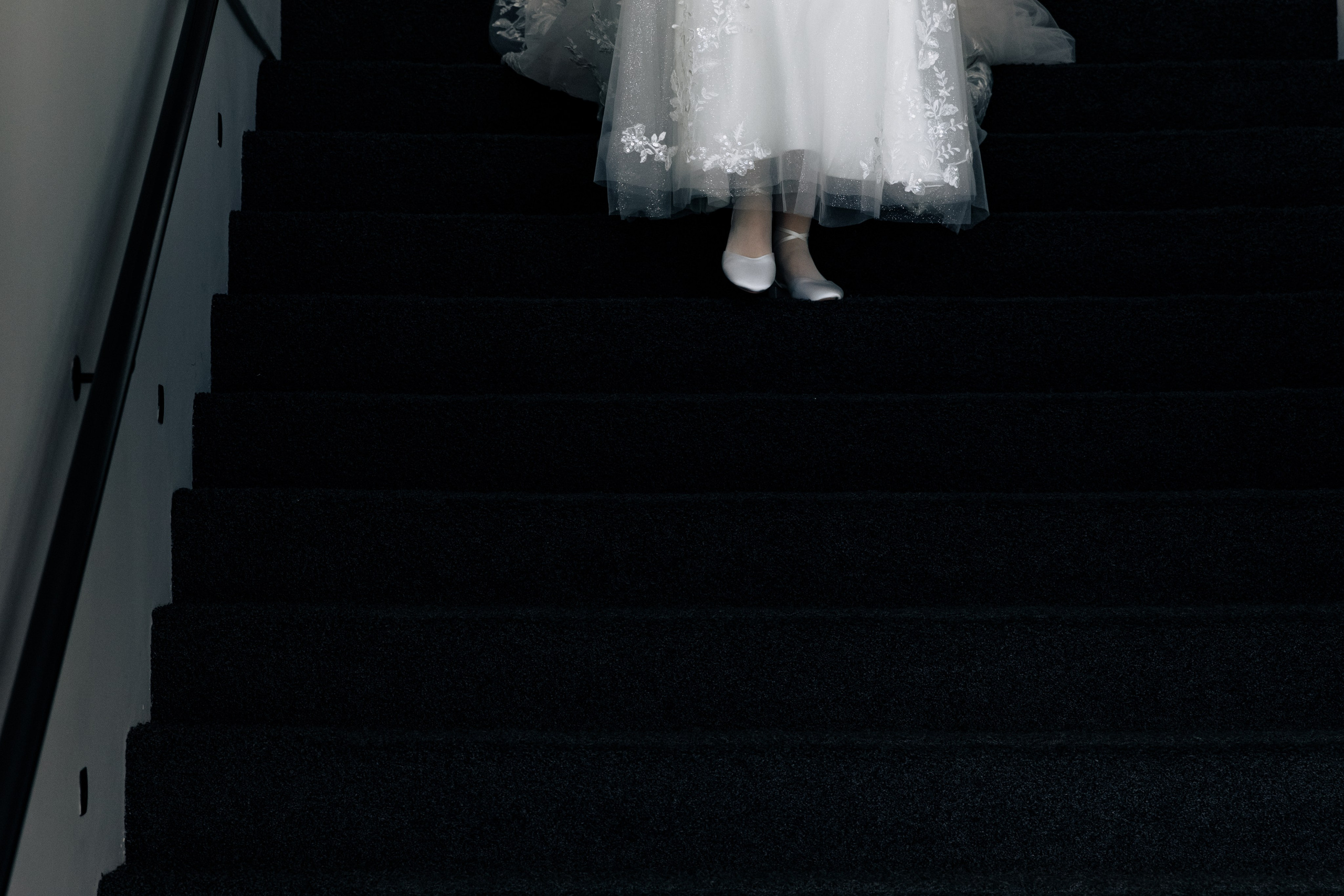 Die Beine der Braut in eleganten Hochzeitsschuhen, die die Treppe hinuntersteigen.