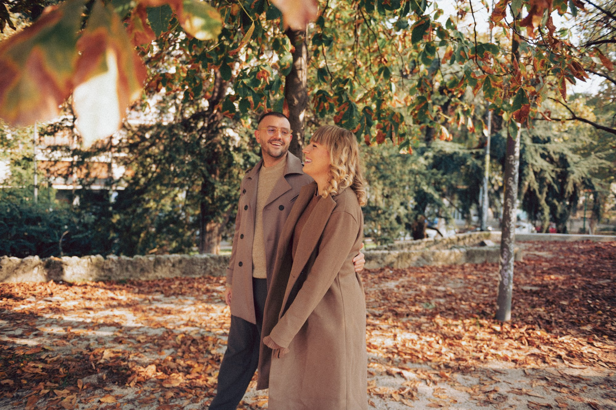 Romantic Autumn Couple Walking — Fall Photoshoot Inspiration. A warm and candid autumn couple photo taken during a walk under golden fall leaves. Natural smiles, soft sunlight, and earthy tones create a cozy, romantic atmosphere. Perfect inspiration for fall couple sessions, lifestyle photography, engagement photos in nature, and warm-toned outdoor portraits. autumn couple photo, fall photoshoot ideas, couple walking photo, cozy fall vibes, romantic autumn photography, candid couple session, fall engagement inspiration, lifestyle couple portraits, warm tones photography, autumn aesthetic