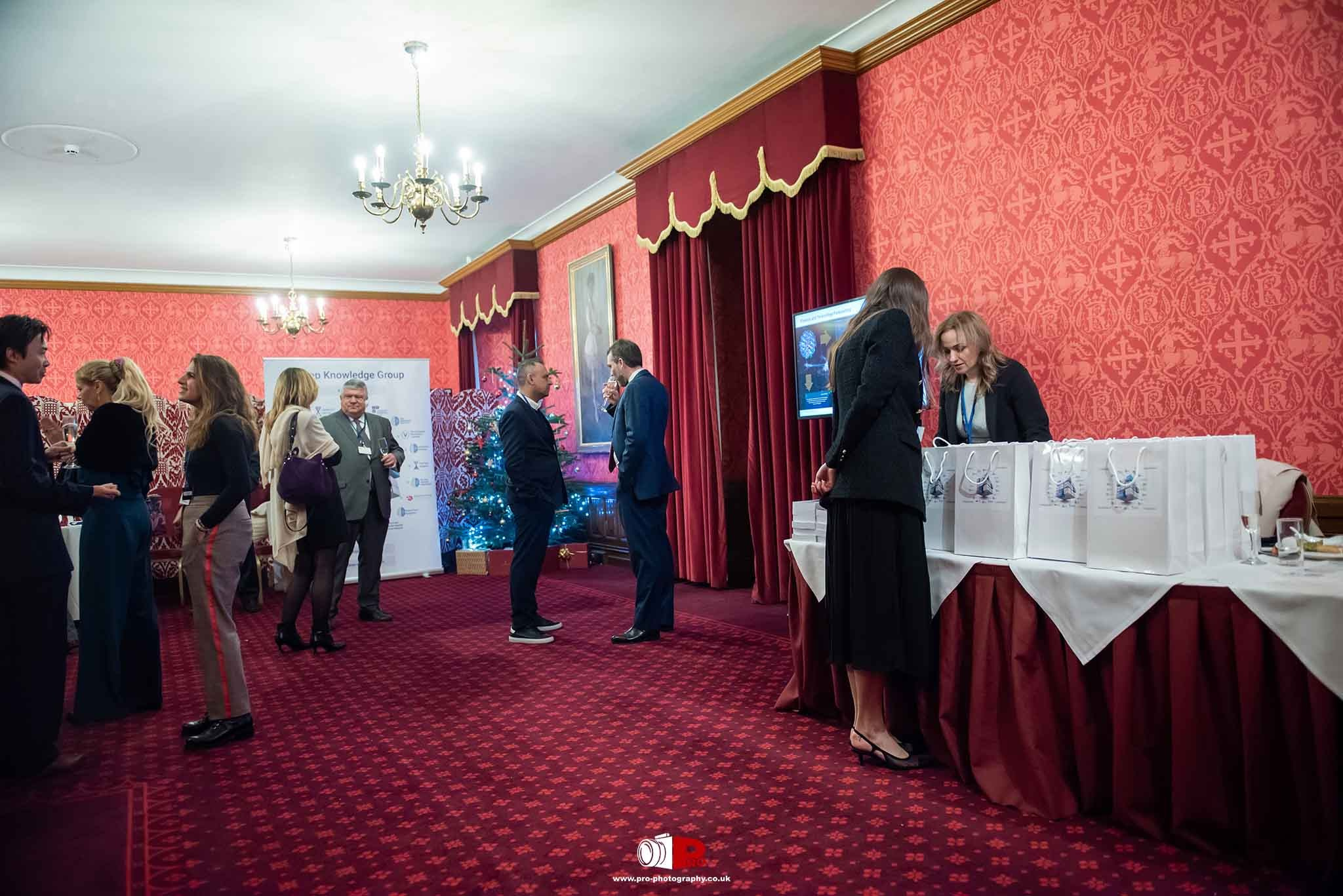 A networking event in a red-themed room featuring business professionals engaging in conversations and exchanging ideas.