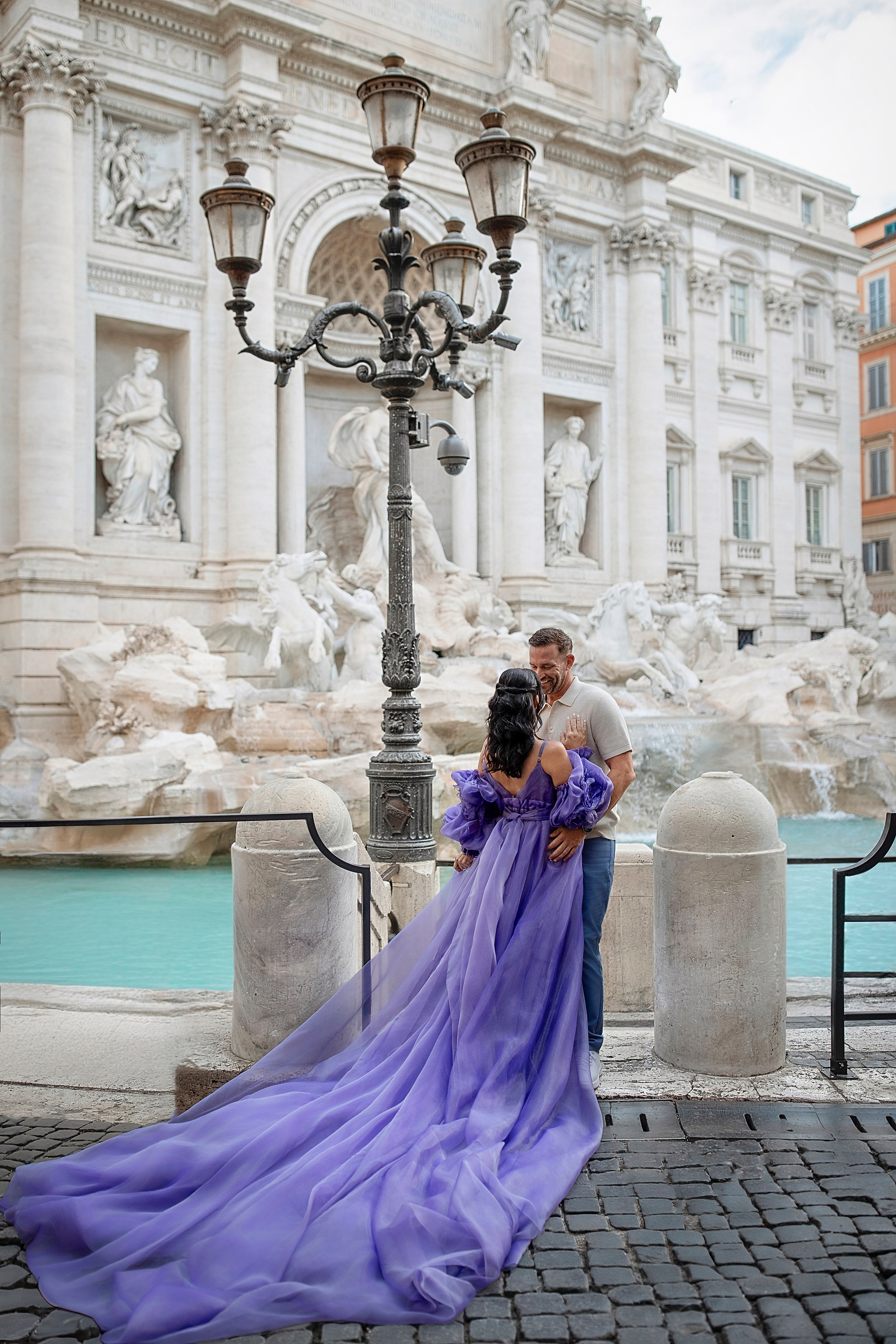 Romantic couple at the Trevi Fountain with the woman in a flying dress during a photoshoot in Rome