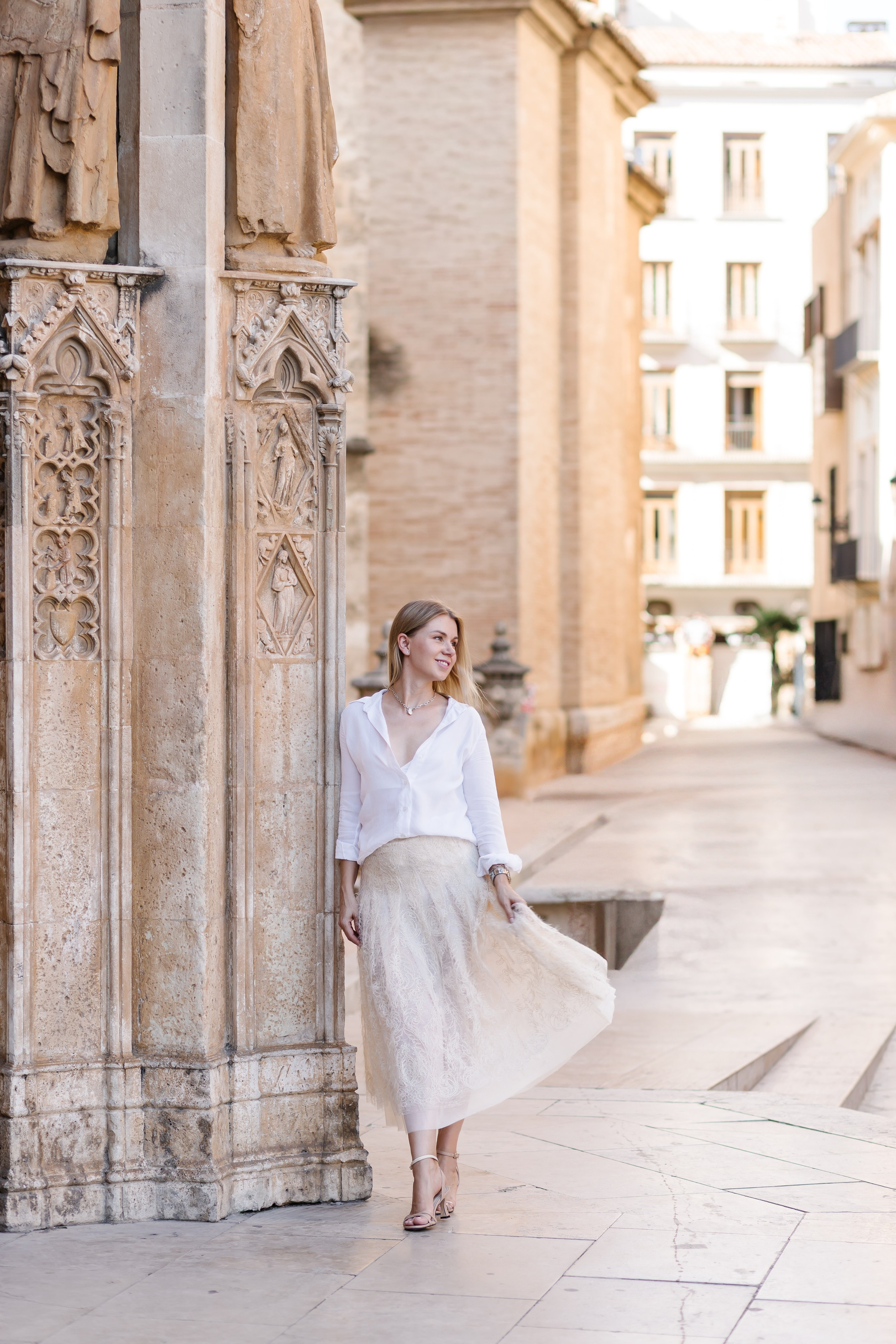 Грациозный женский портрет в воздушном белом наряде, снятый у исторической архитектуры в центре Валенсии, Испания — идеальное вдохновение для элегантных женских портретных фотосессий в Валенсии и по всей Испании.