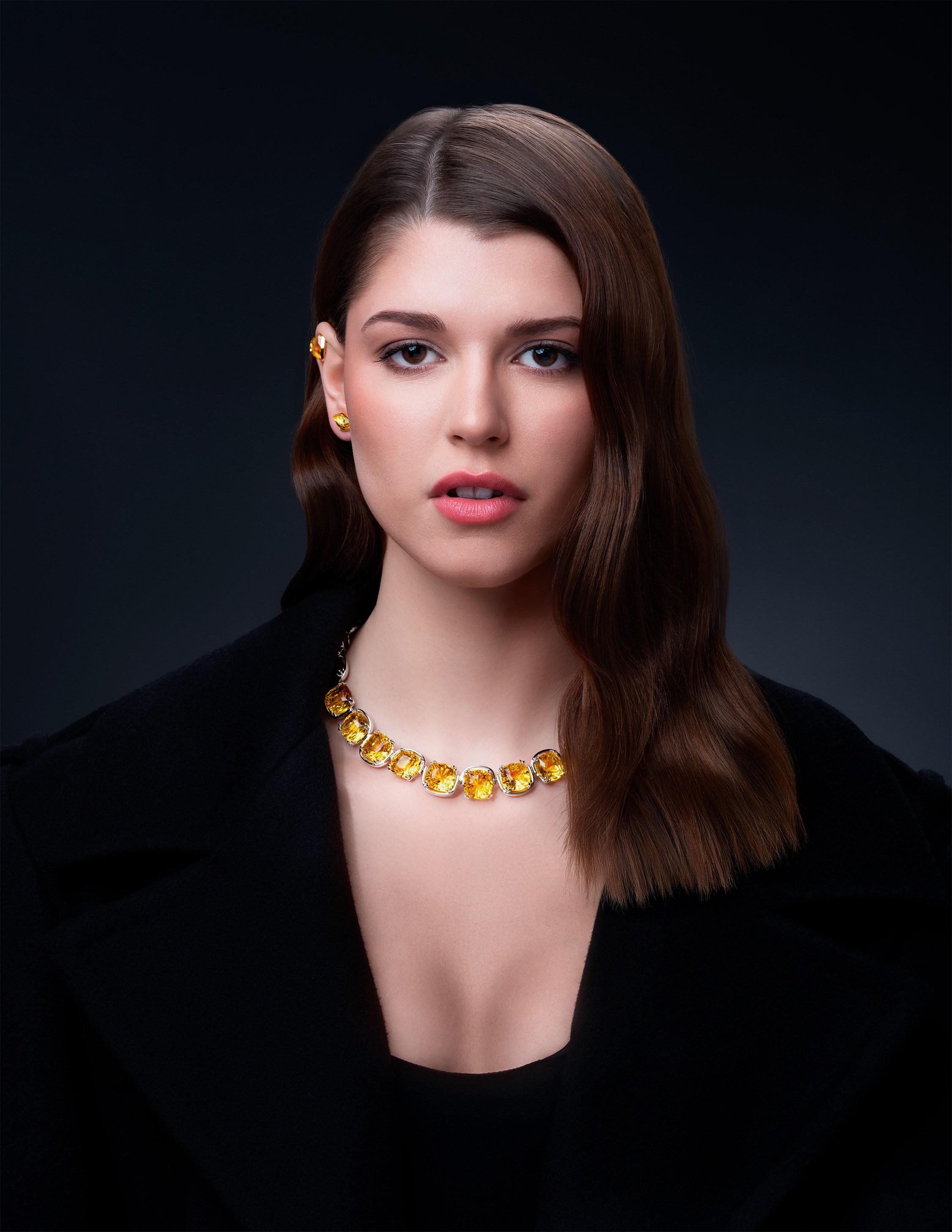 High-fashion portrait of a model wearing a radiant Swarovski yellow gemstone necklace, paired with a sleek black outfit for an elegant luxury look.
