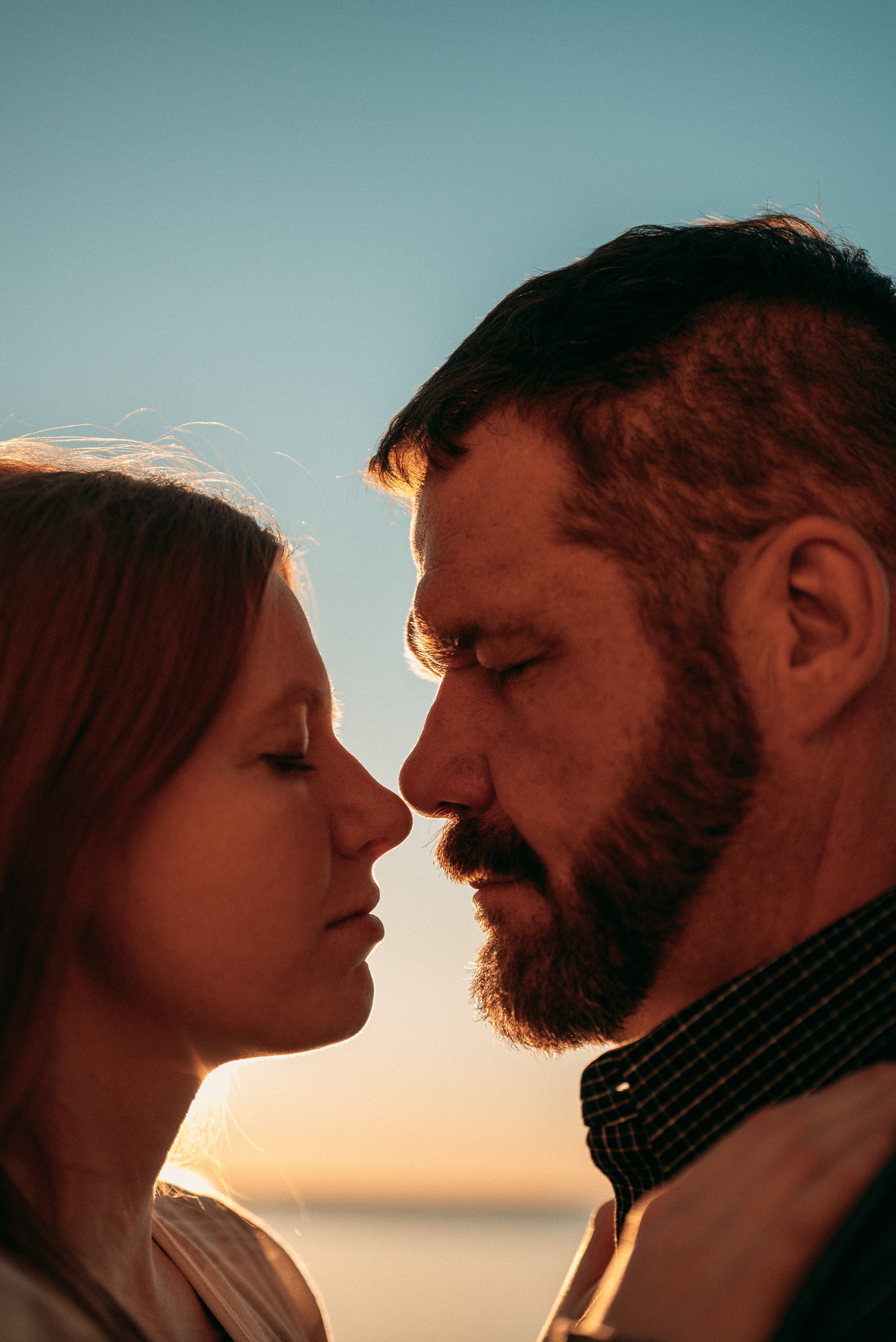 Couple sharing a quiet moment in Green Bay’s scenic waterfront, reflecting their love story amidst blooming flowers.