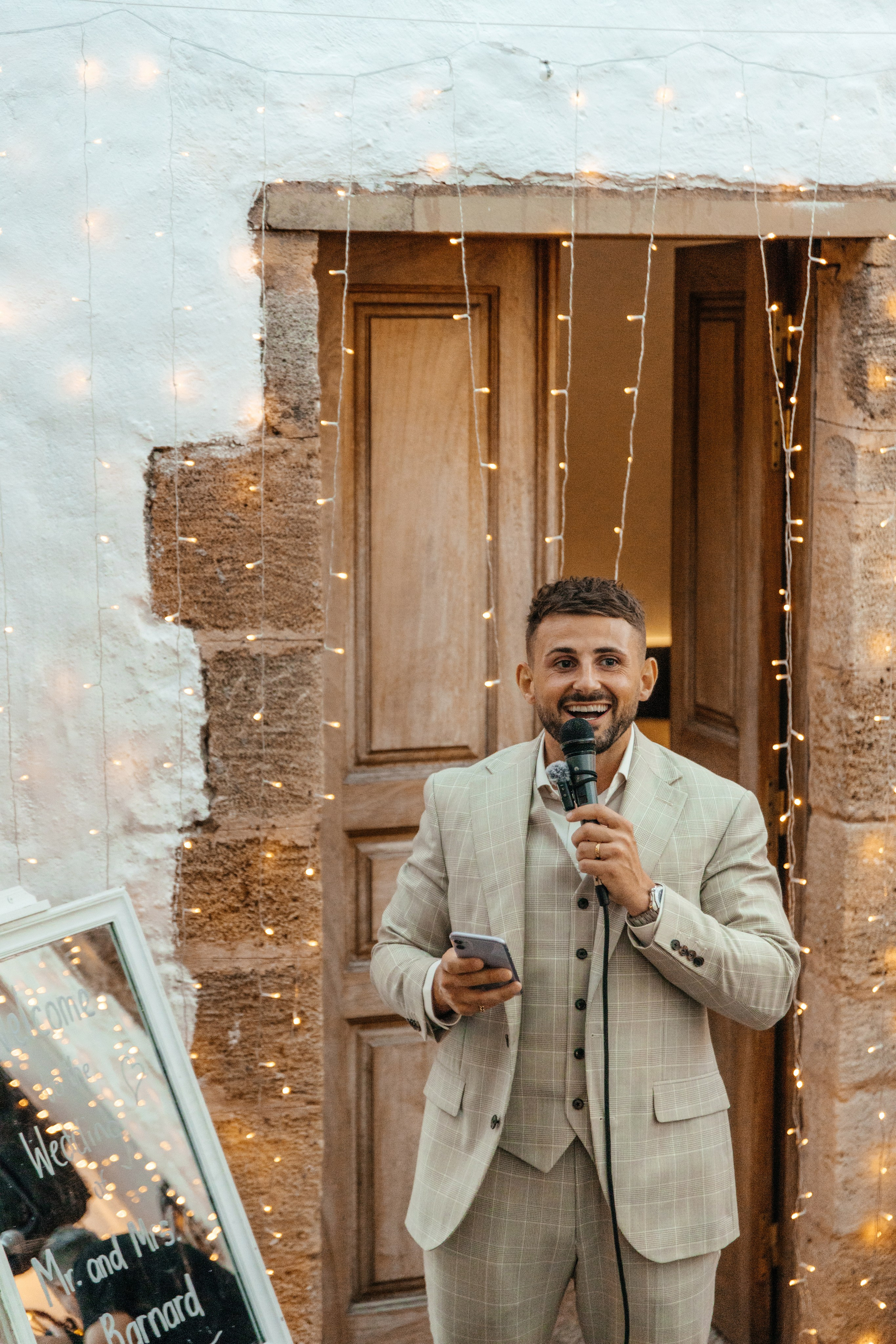 Groom is giving a touching speech at his wedding reception in a traditional Greek restaurant in Lindos, with guests raising their glasses