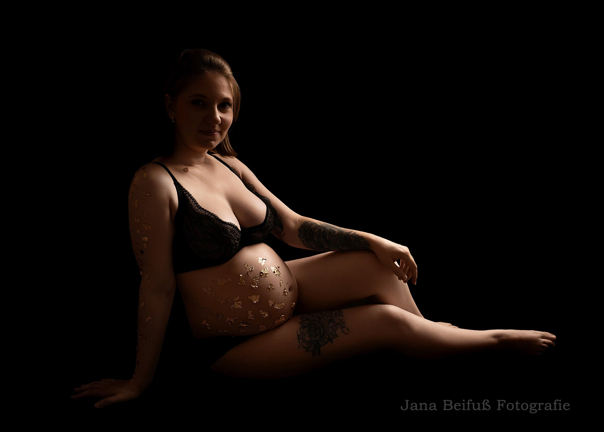 werdende Mama sitzt in schwarzer Unterwäsche beim Babybauchshooting bei Jana Beifuß in Weißenhorn bei Ulm - Schwangerschaftsfotografie Weißenhorn bei Ulm