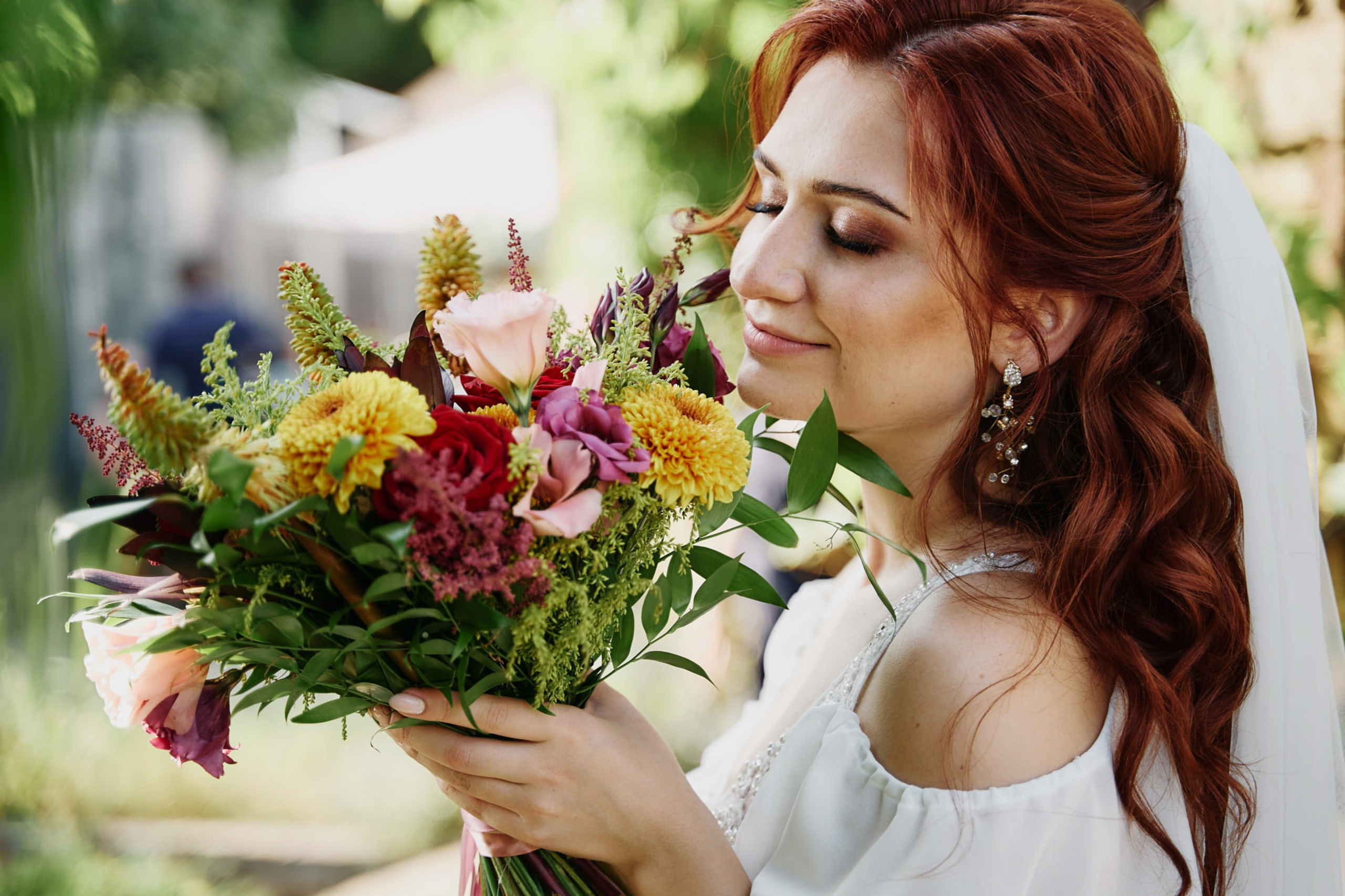 Red-haired bride smelling bouquet, joyful wedding portrait
