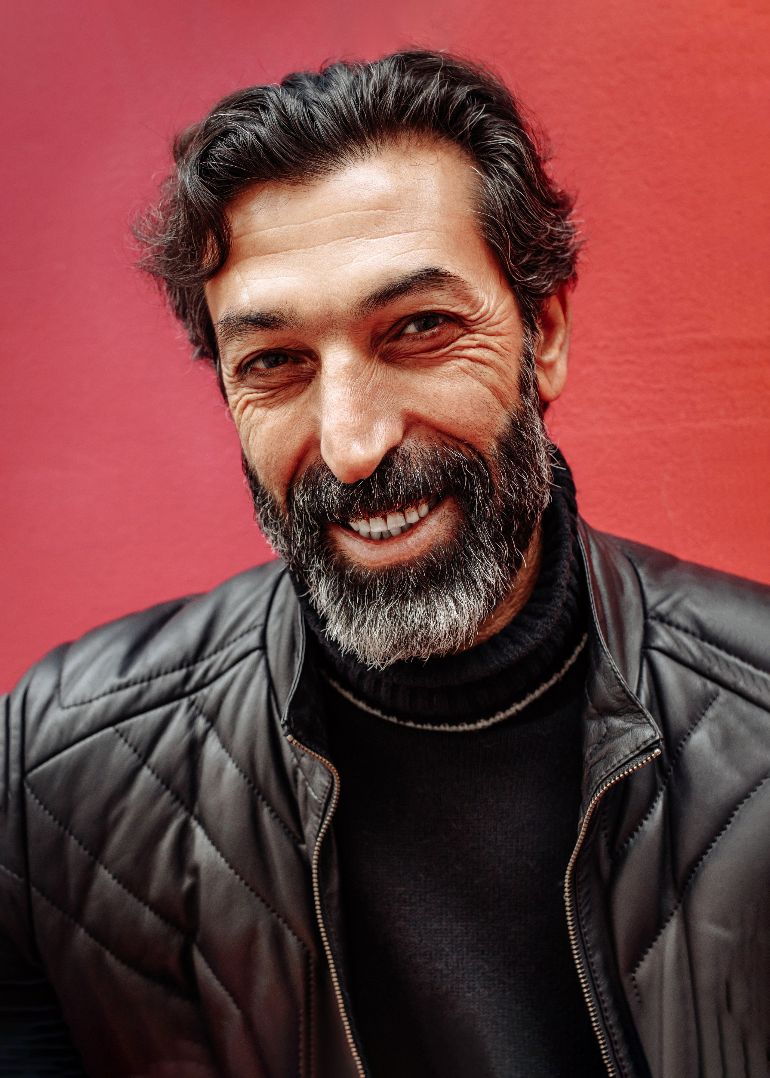 Крупный портрет улыбающегося мужчины на красном фоне