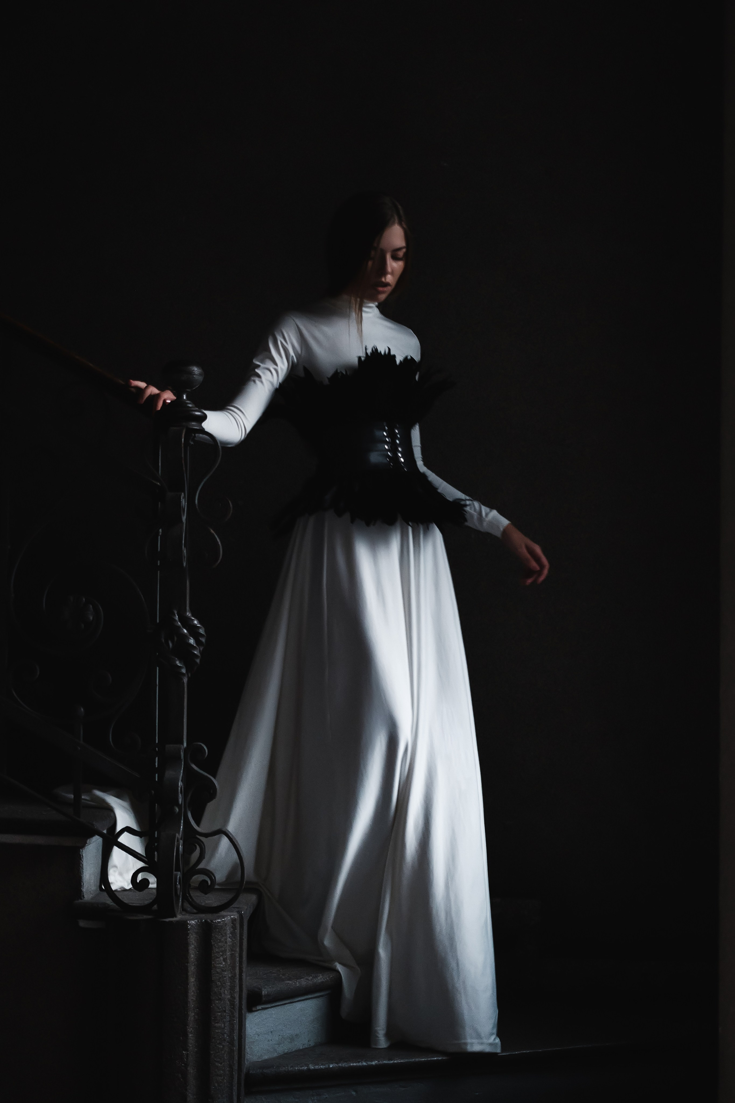 Moody fashion campaign portrait with a monochrome black corset gown on a historic staircase