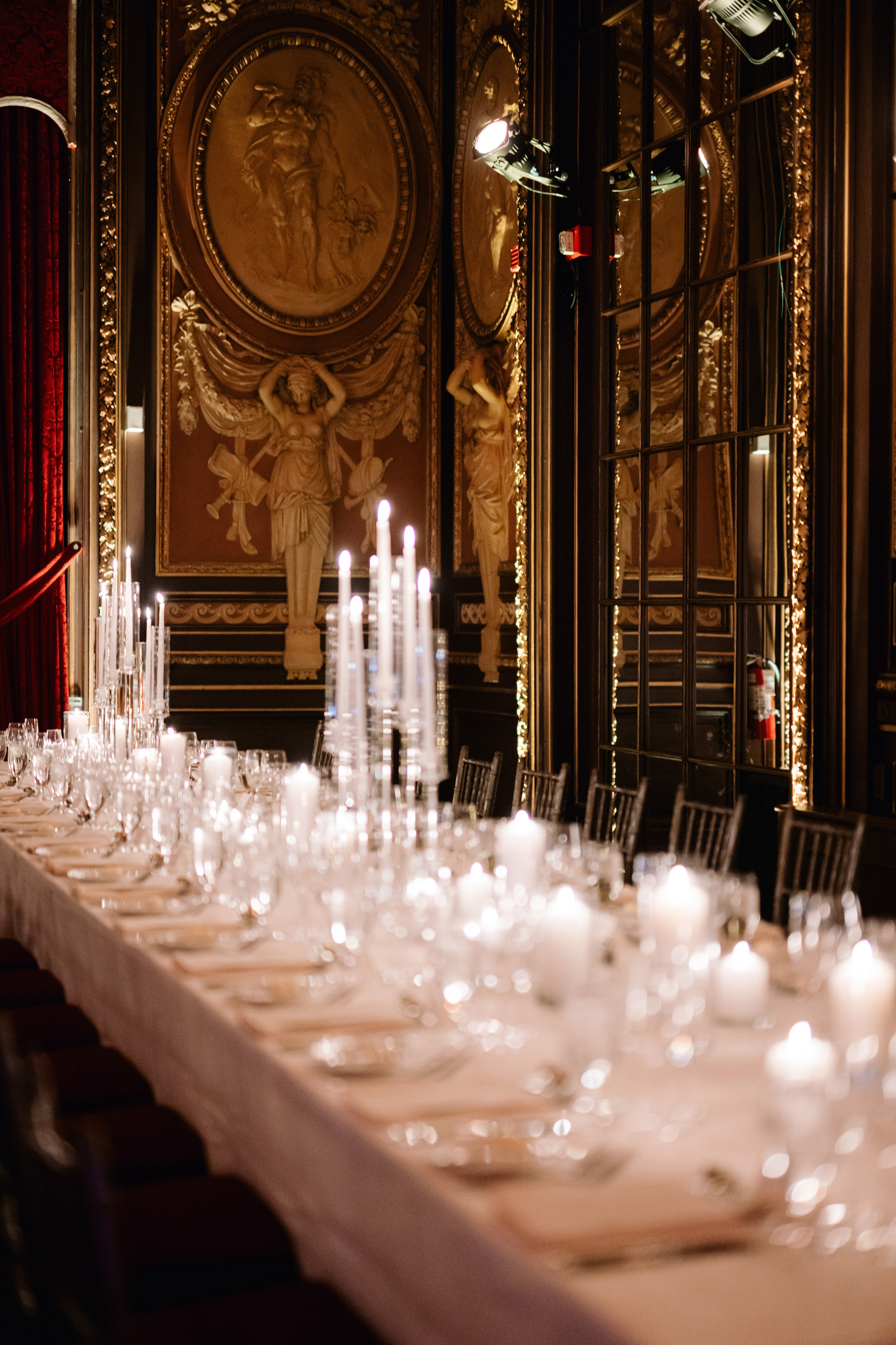 a long table with white plates and candles