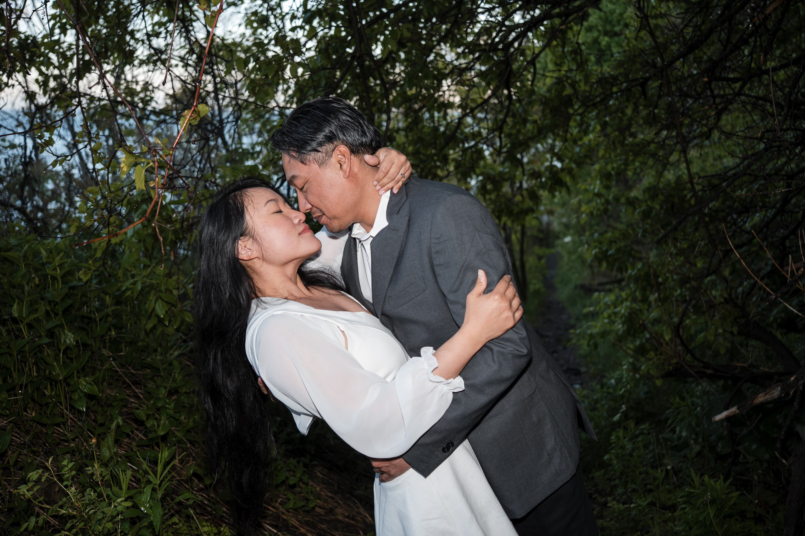 Engaged couple sharing an intimate moment, about to kiss during their engagement photoshoot in a forest.