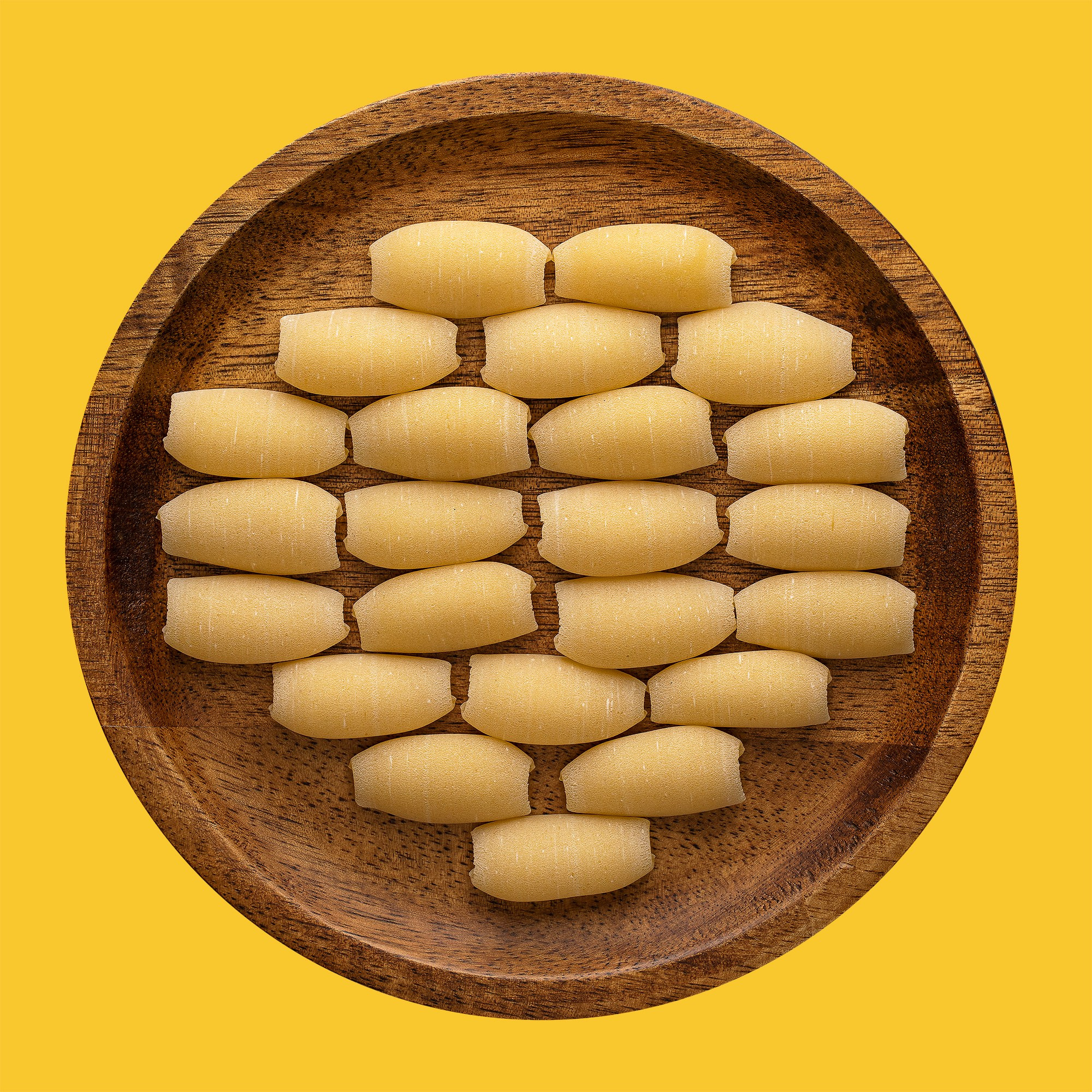 Photographer Roman Djuzev - Cavatelli lisci pasta on a wooden plate, shot in high key, on a white background.