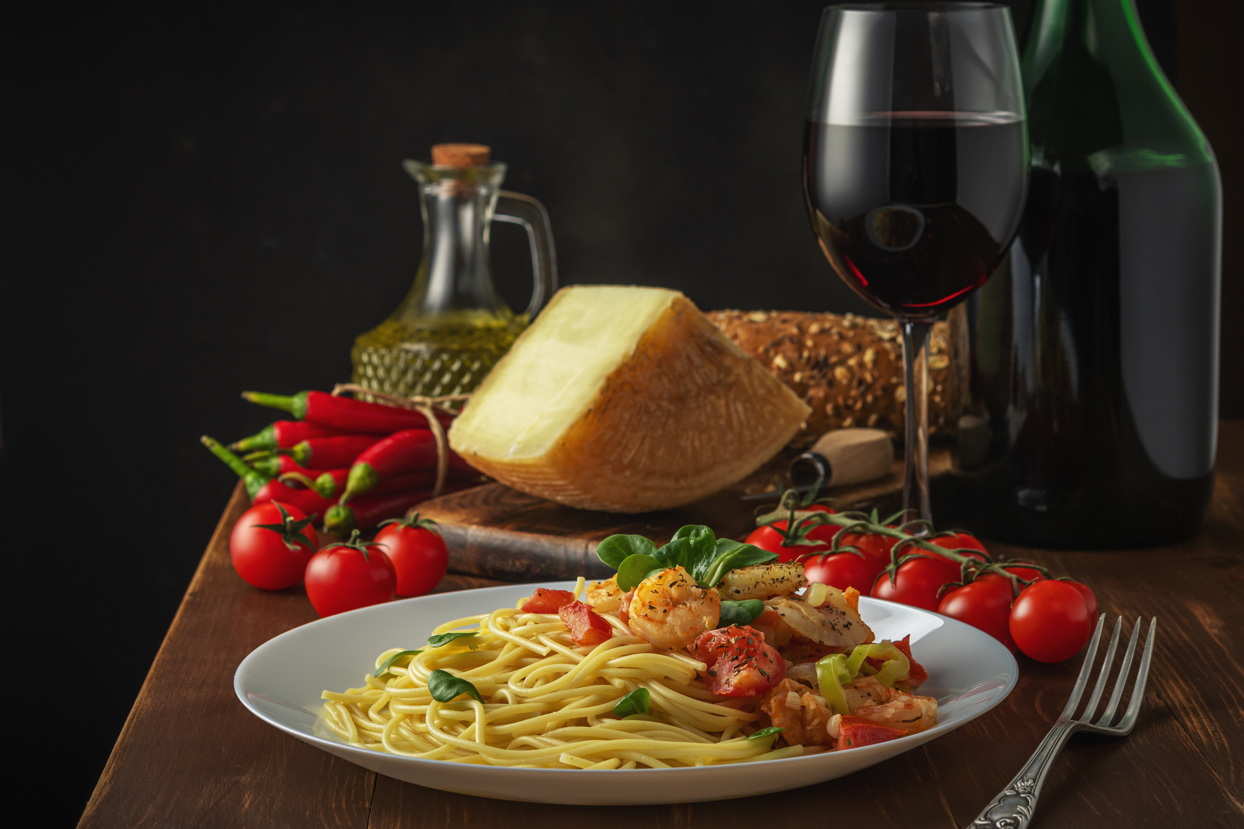 Spaghetti with shrimps, cherry tomatoes and spices on wooden background.