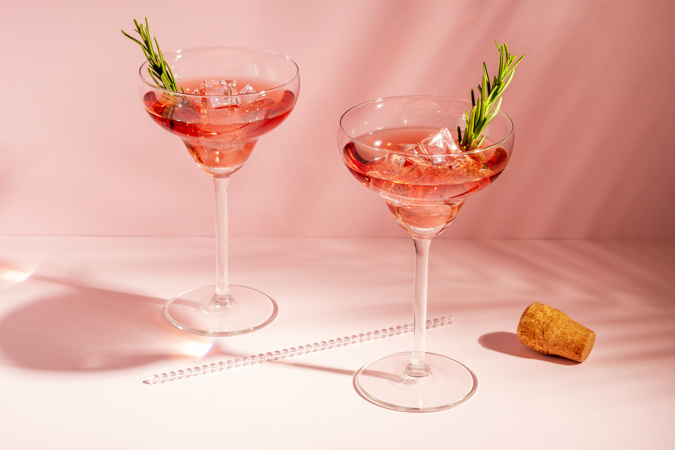 Refreshing cocktail with rosemary in a glass on a bright background.