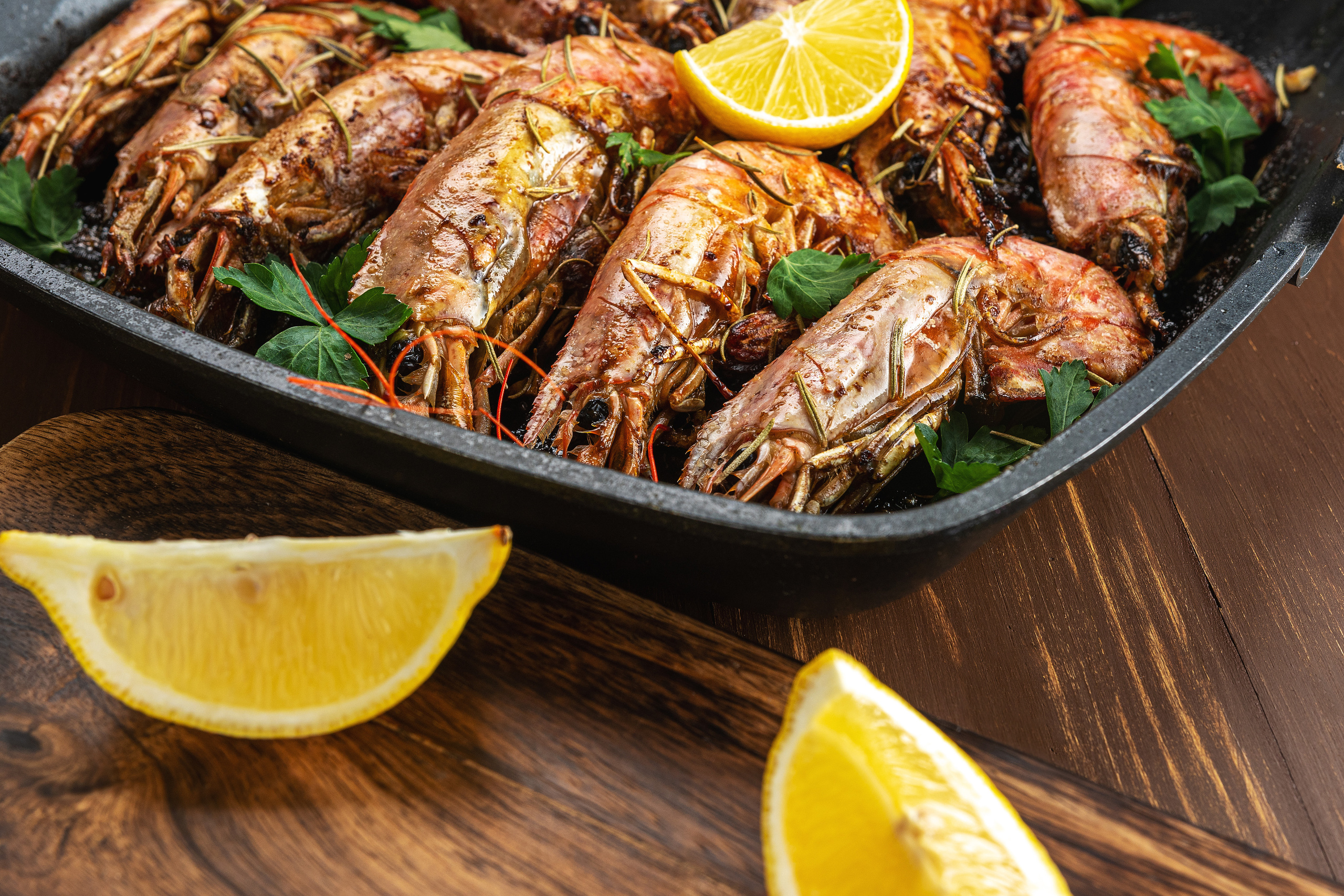 Fried shrimps on grill pan with fresh herbs and lemon slice.