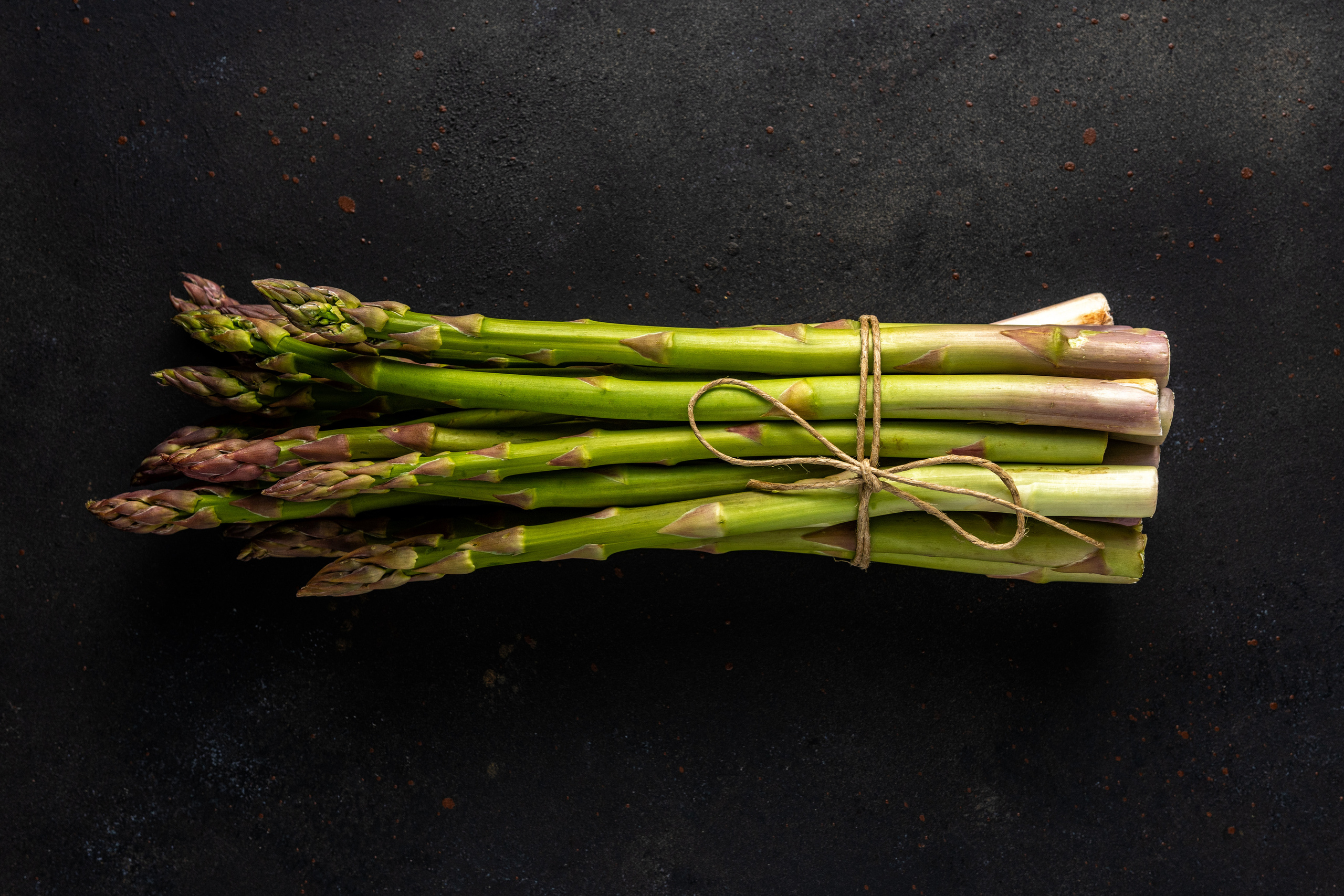 View of fresh asparagus on a black table.