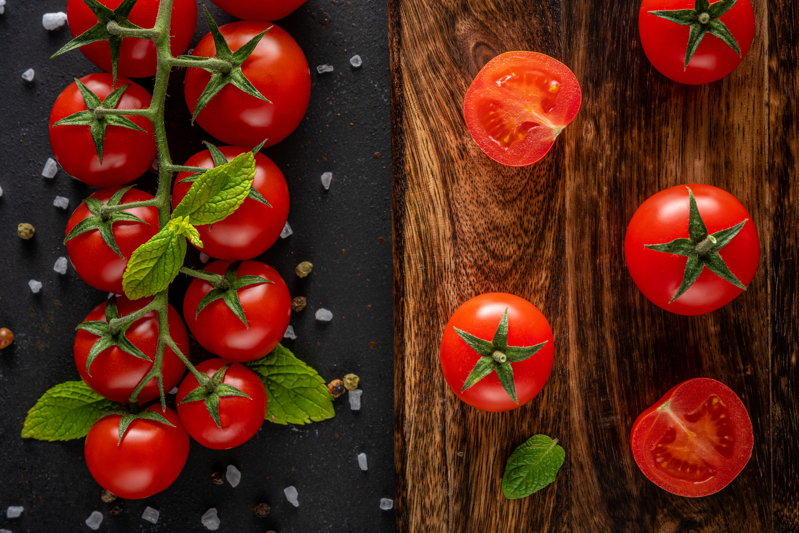 Fresh cherry tomatoes on a black background with spices.