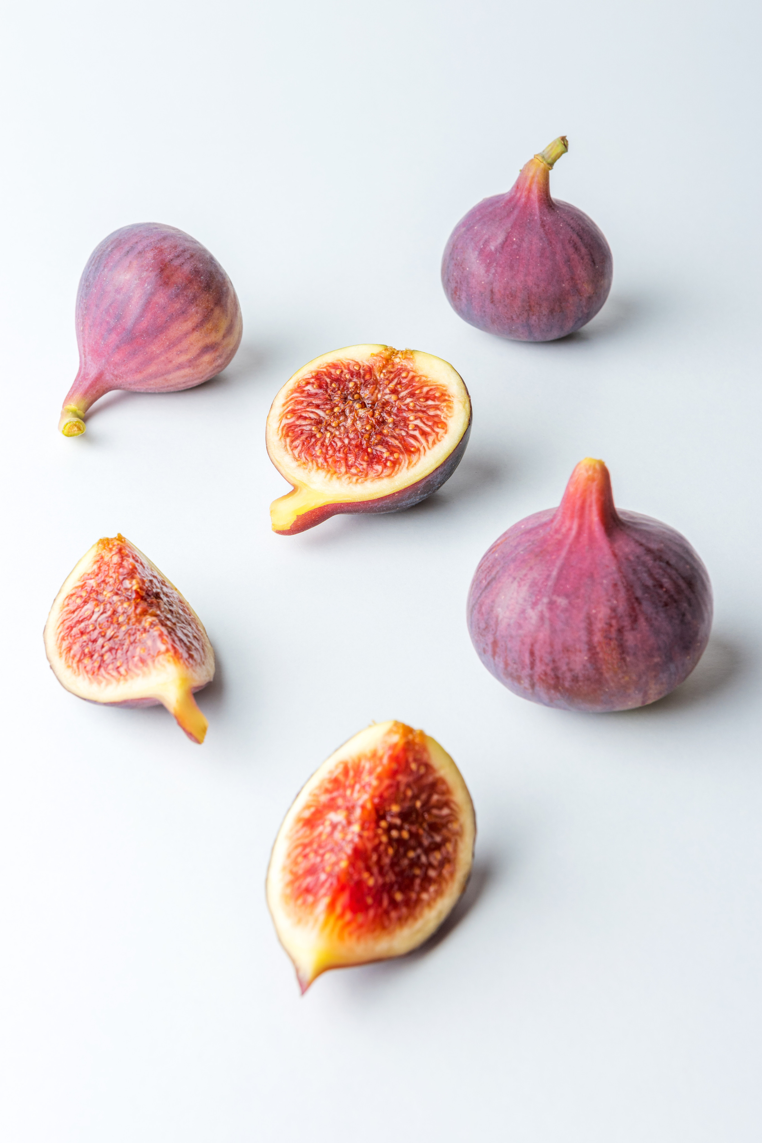 Composition with whole and cut figs on white background.