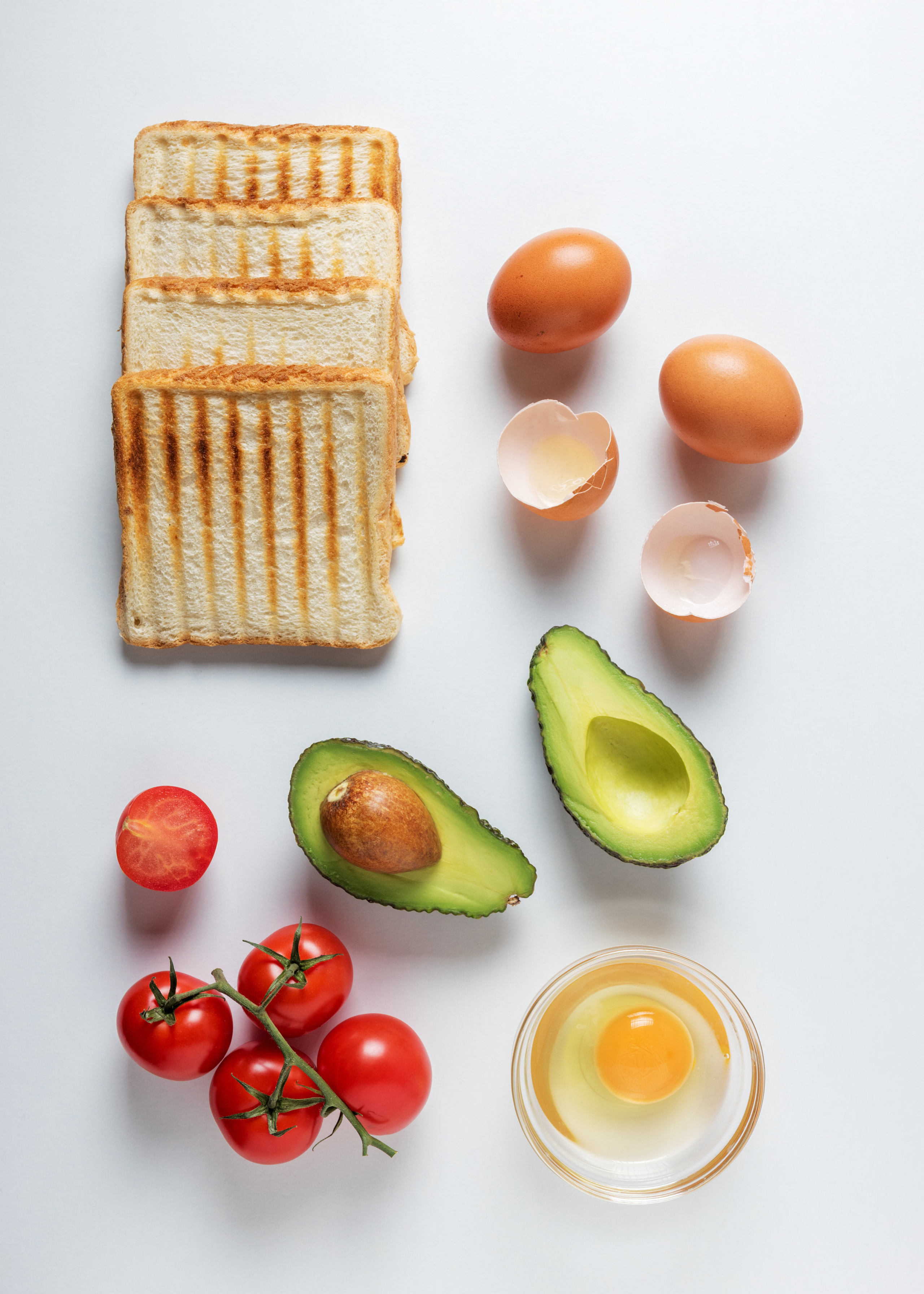 Creative layout of breakfast sandwiches with avocado, eggs and cherry tomatoes.