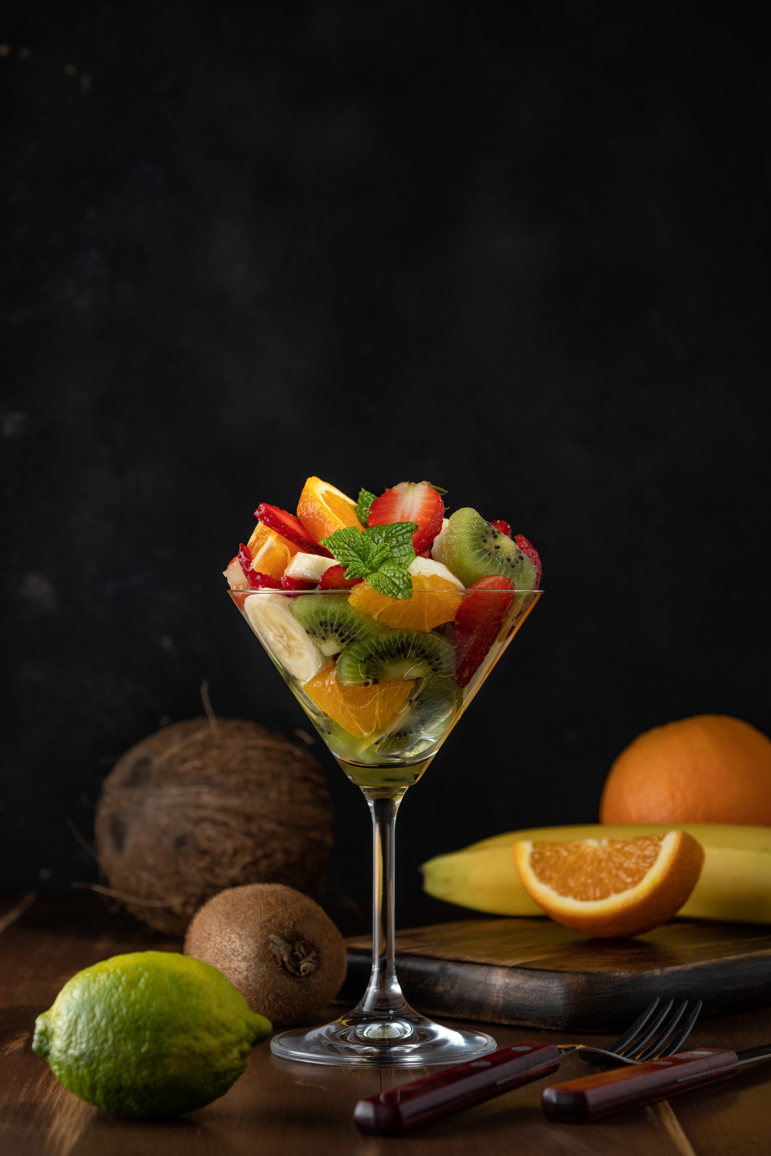 Fruit cocktail in martini glass on wooden table.