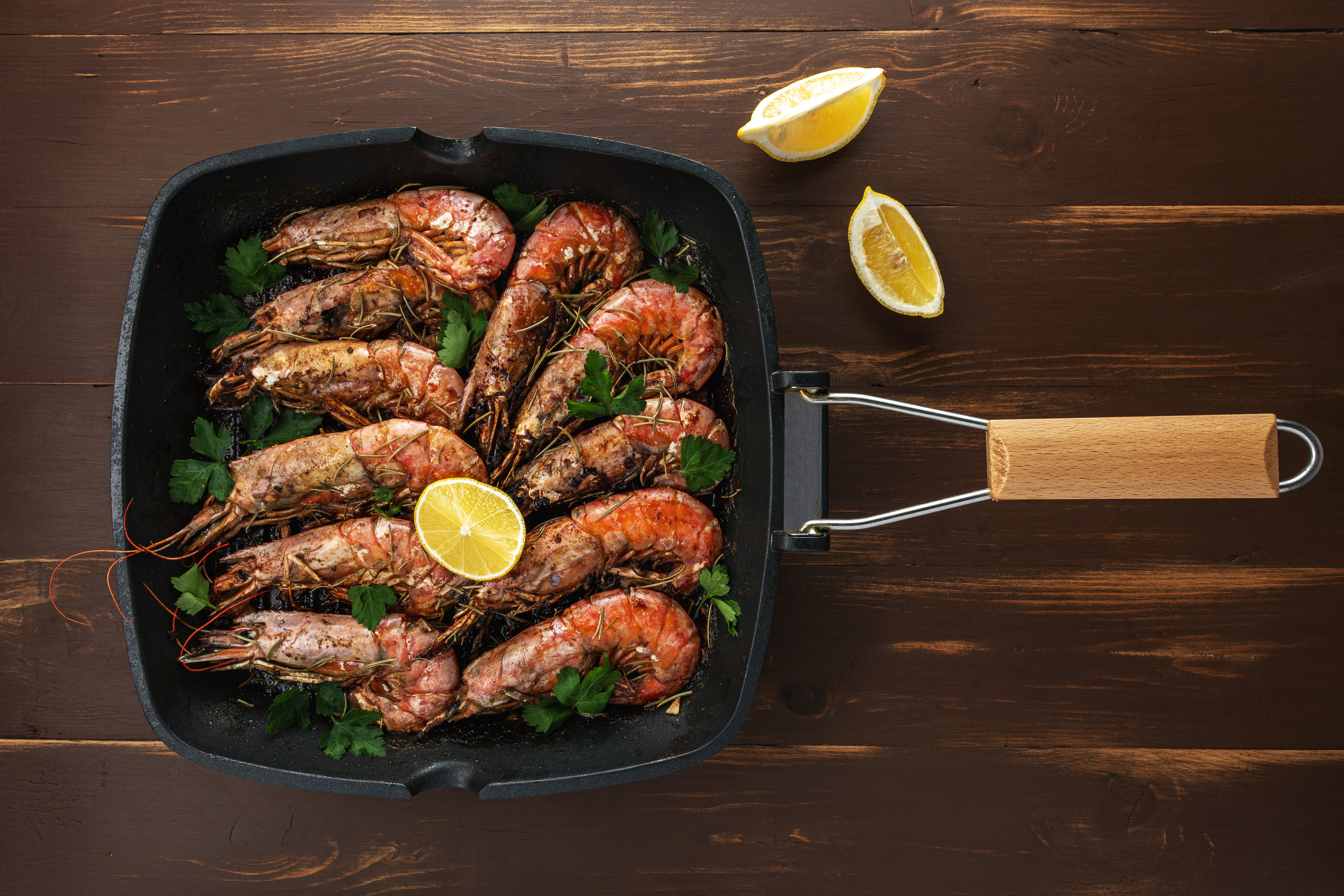 Fried shrimps on grill pan with fresh herbs and lemon slice.