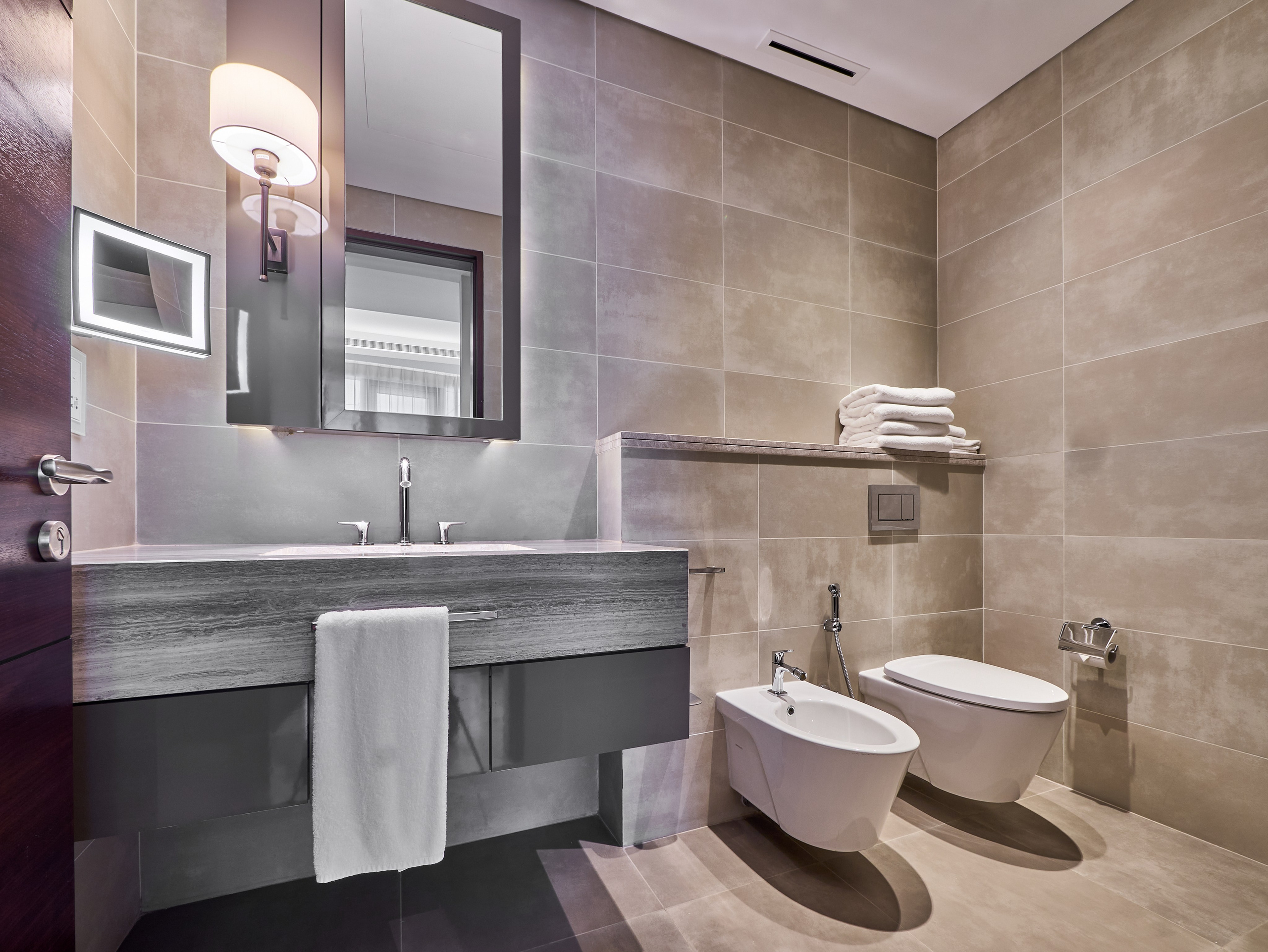 Elegant guest bathroom with modern bidet, wall-mounted toilet and stylish vanity — photographed for upscale rental and real estate showcases.