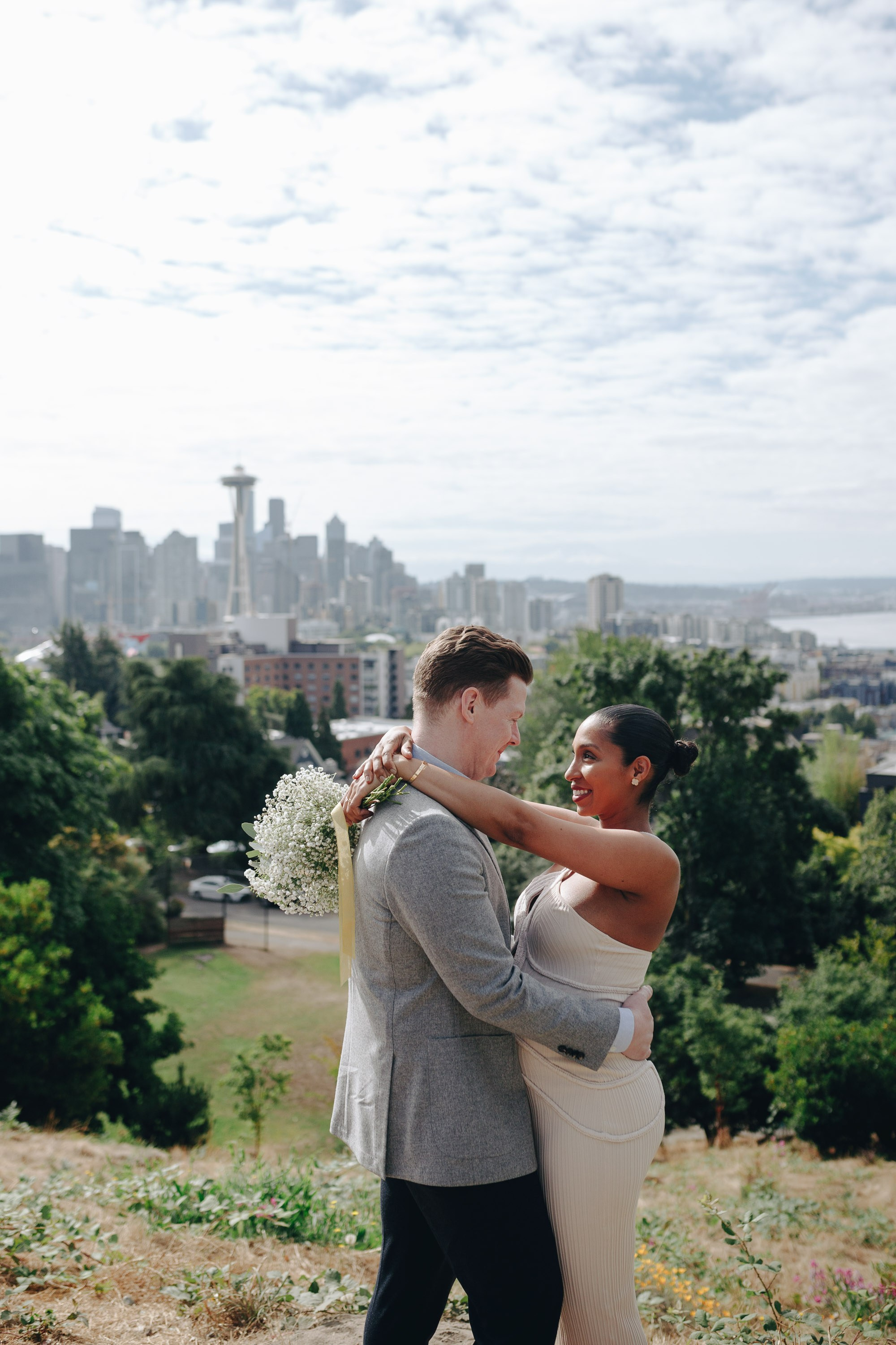 Bride and groom embracing with city skyline in background
