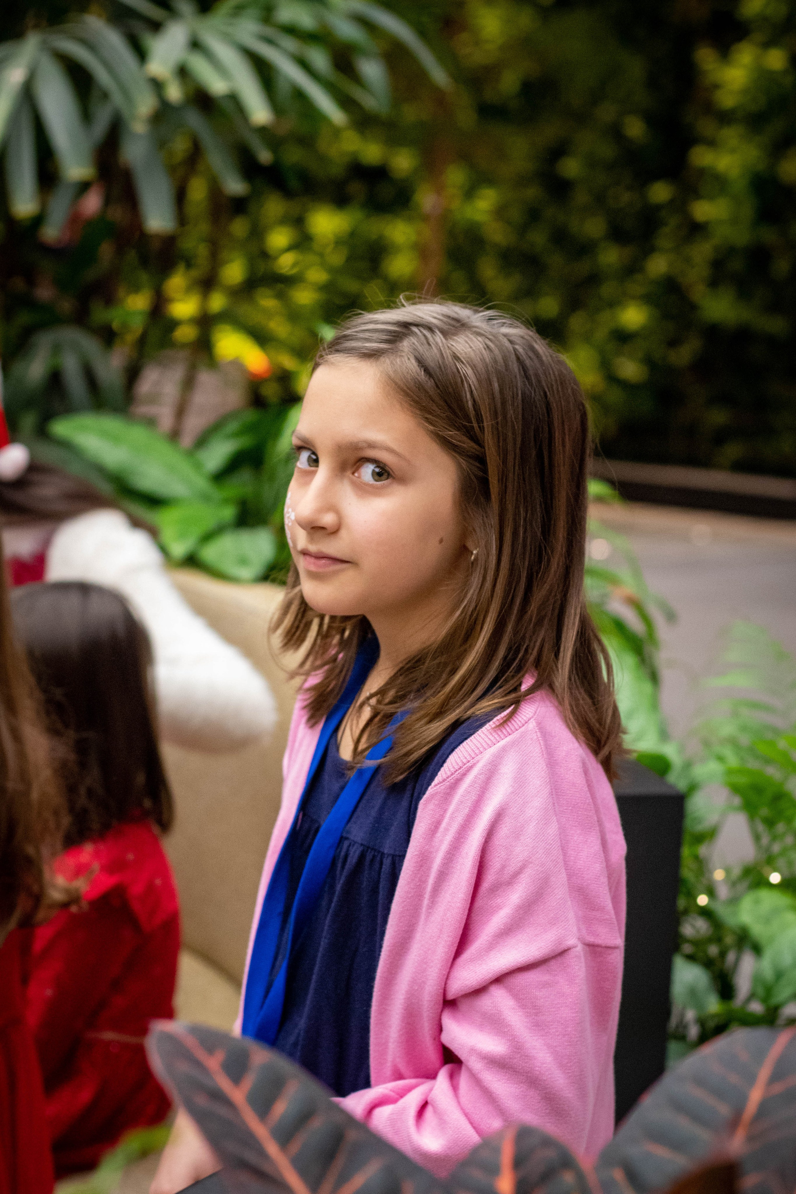 Young girl with a backpack looking focused at an indoor children's event.