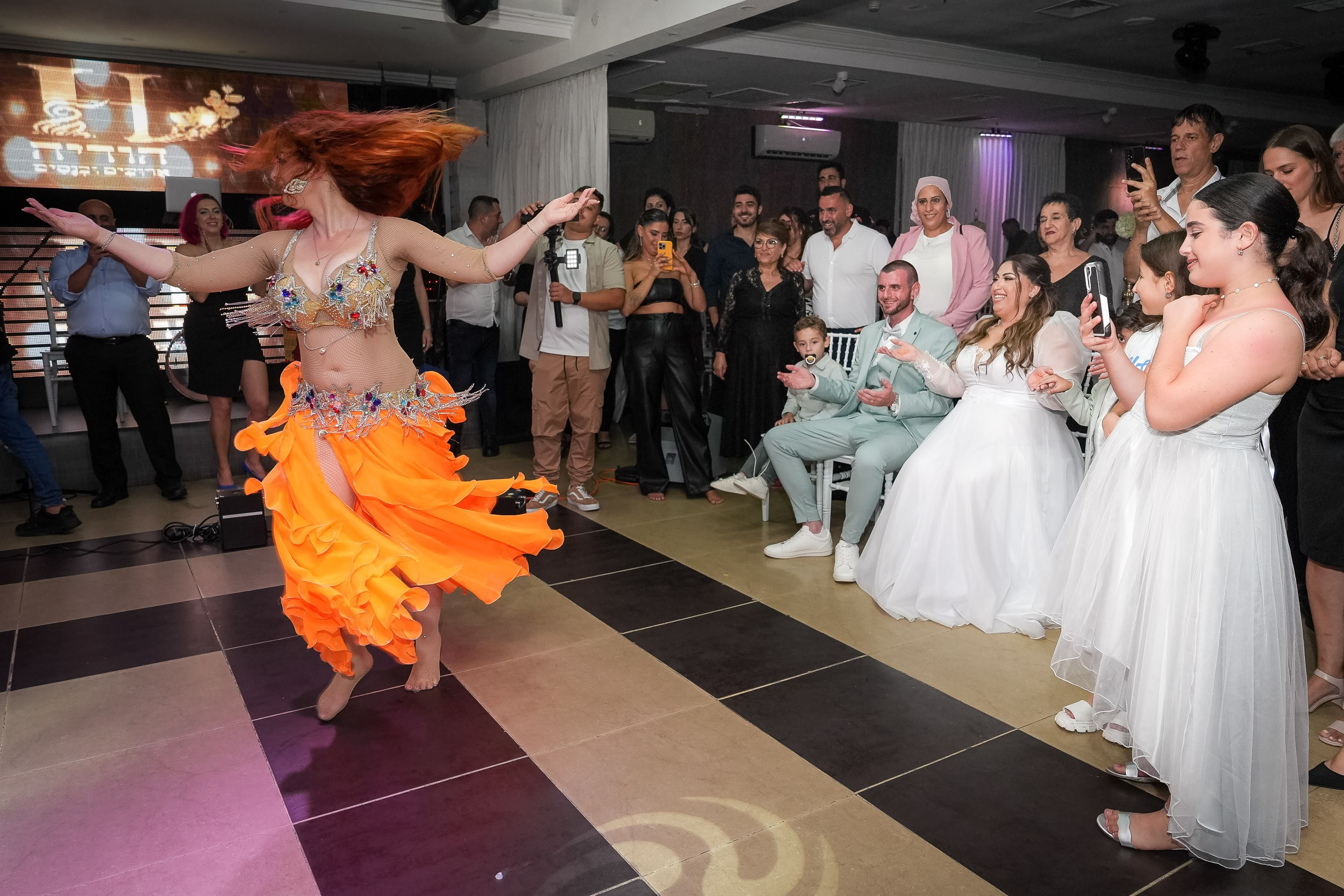 A belly dancer performs for Ella, Matan, and their wedding guests