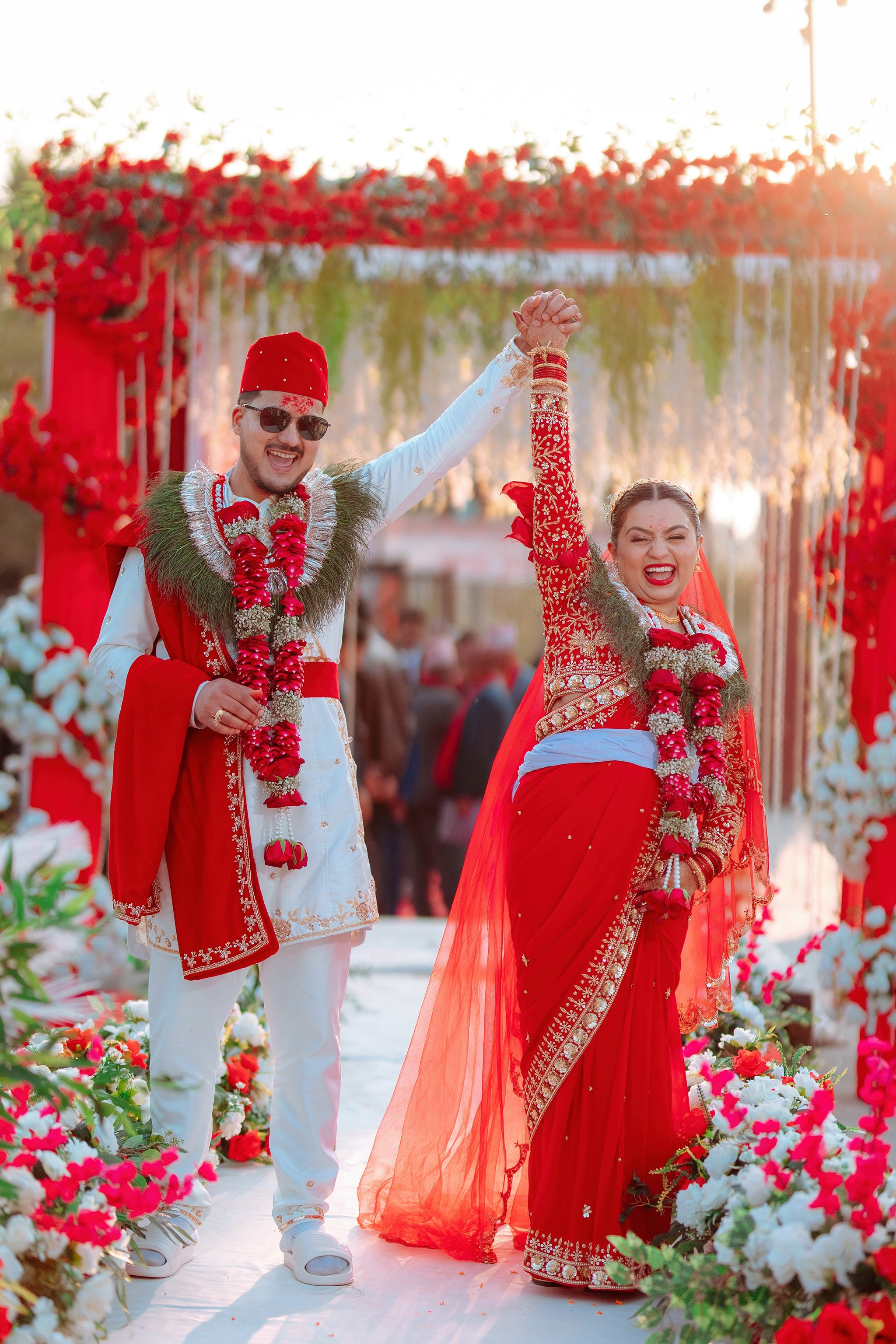 cheers to forever. happy Nepali bride and groom raise hands in celebration on stage, premium wedding shoot