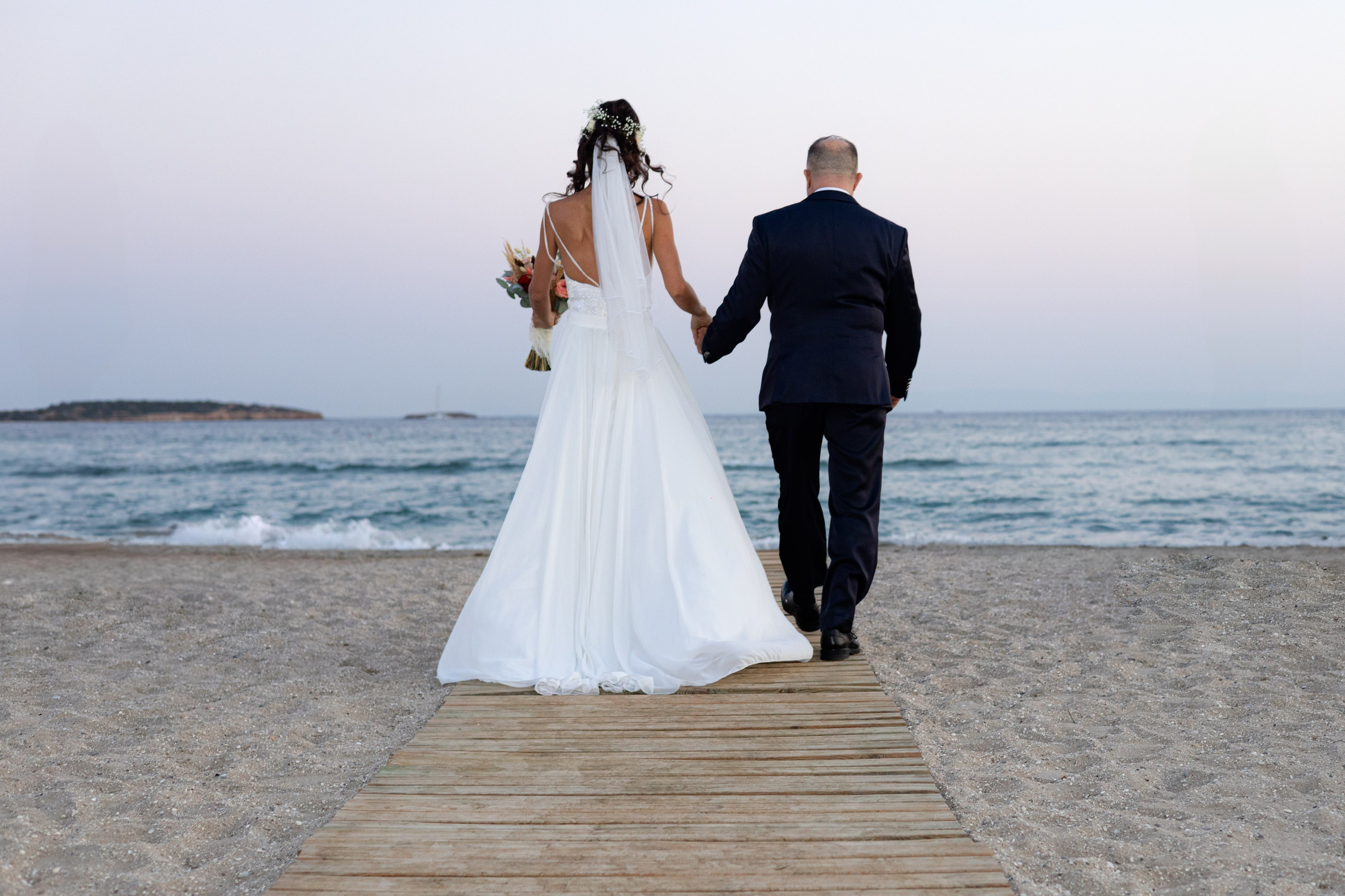 Bride and groom walking together after their seaside wedding ceremony