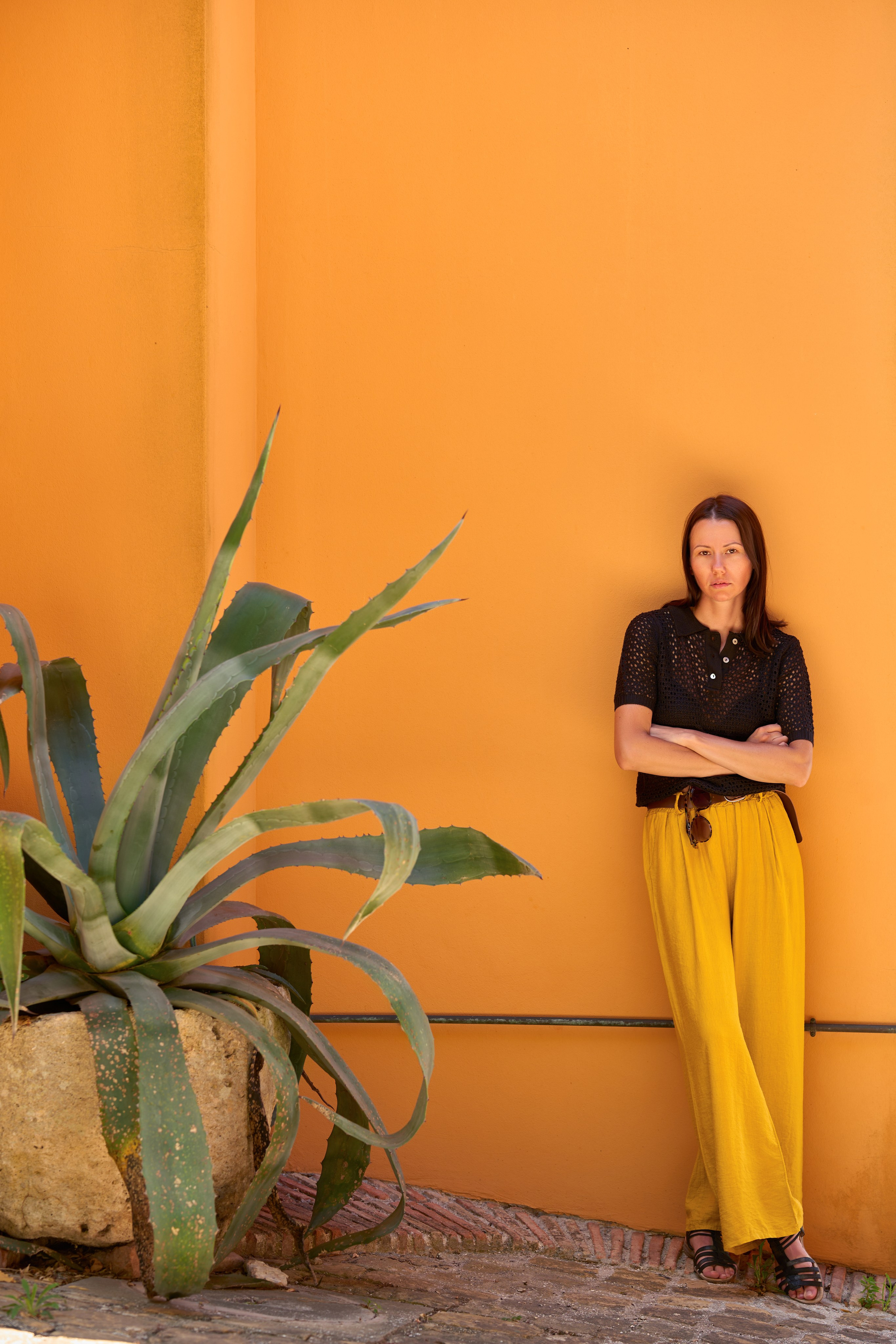 Model in gelber Hose vor gelber Wand in Italien