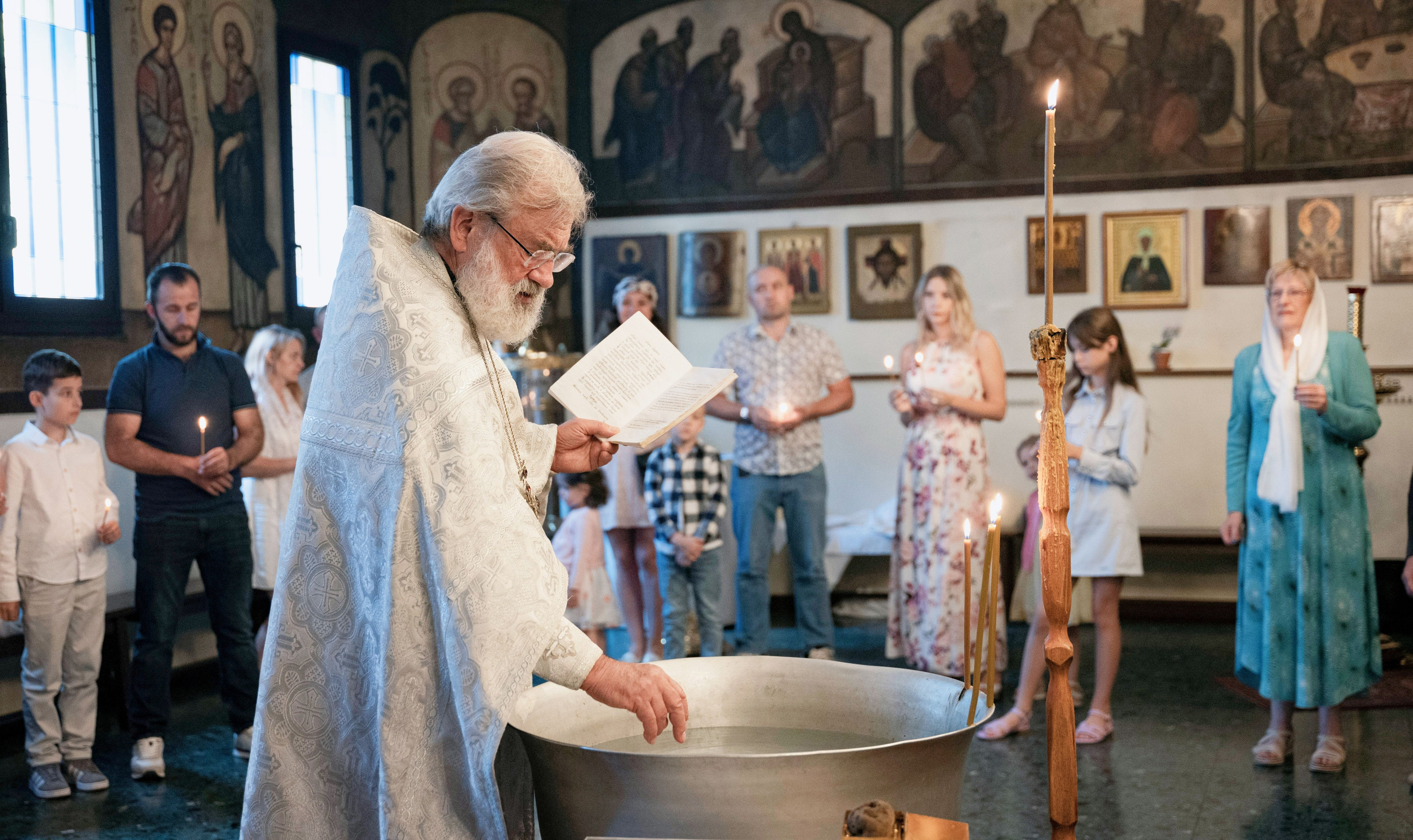 An Orthodox priest says a prayer over a vat of holy water, he prepares the rite of the child's baptism.