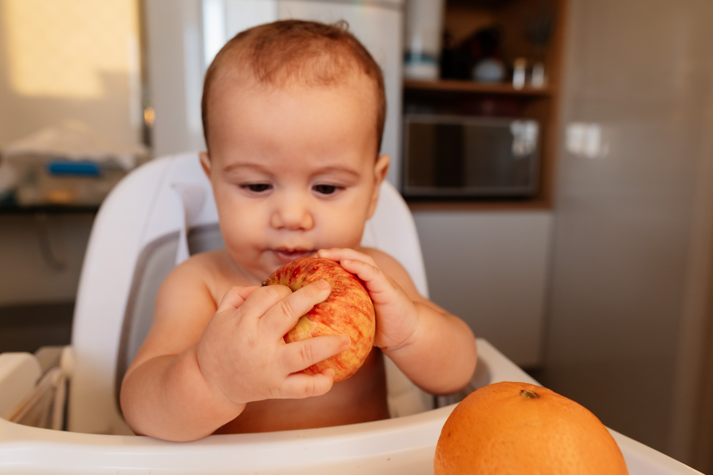 Bebê explora alimento com as mãos.