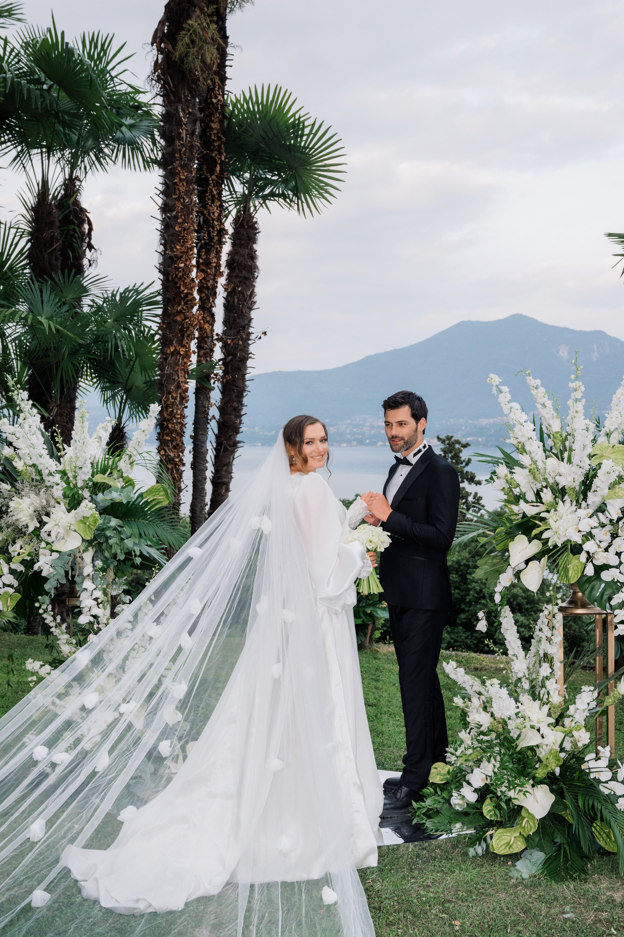 a bride and groom standing in front of a floral arch