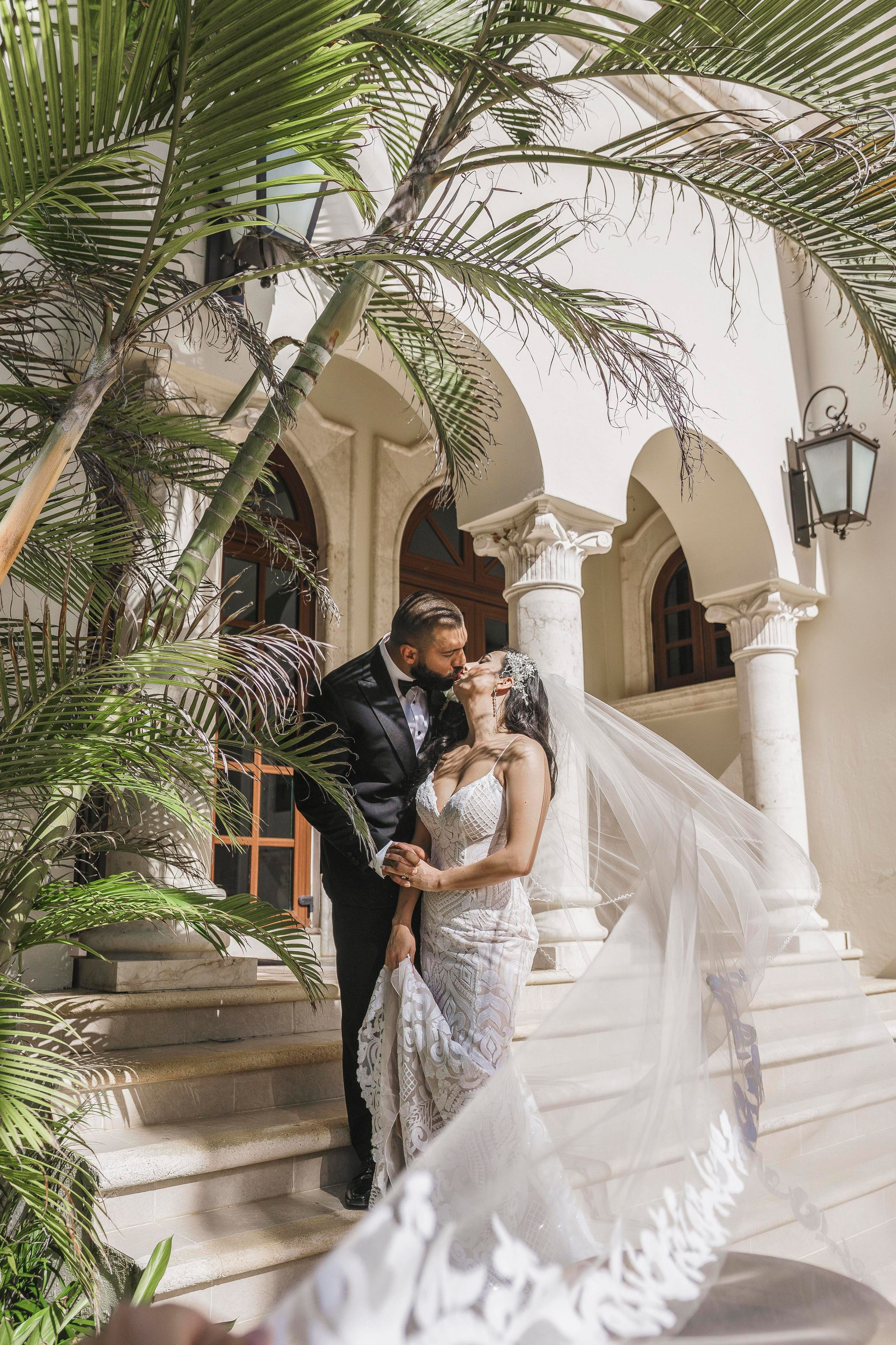 Wedding couple kissing on steps of luxury hacienda in Riviera Maya