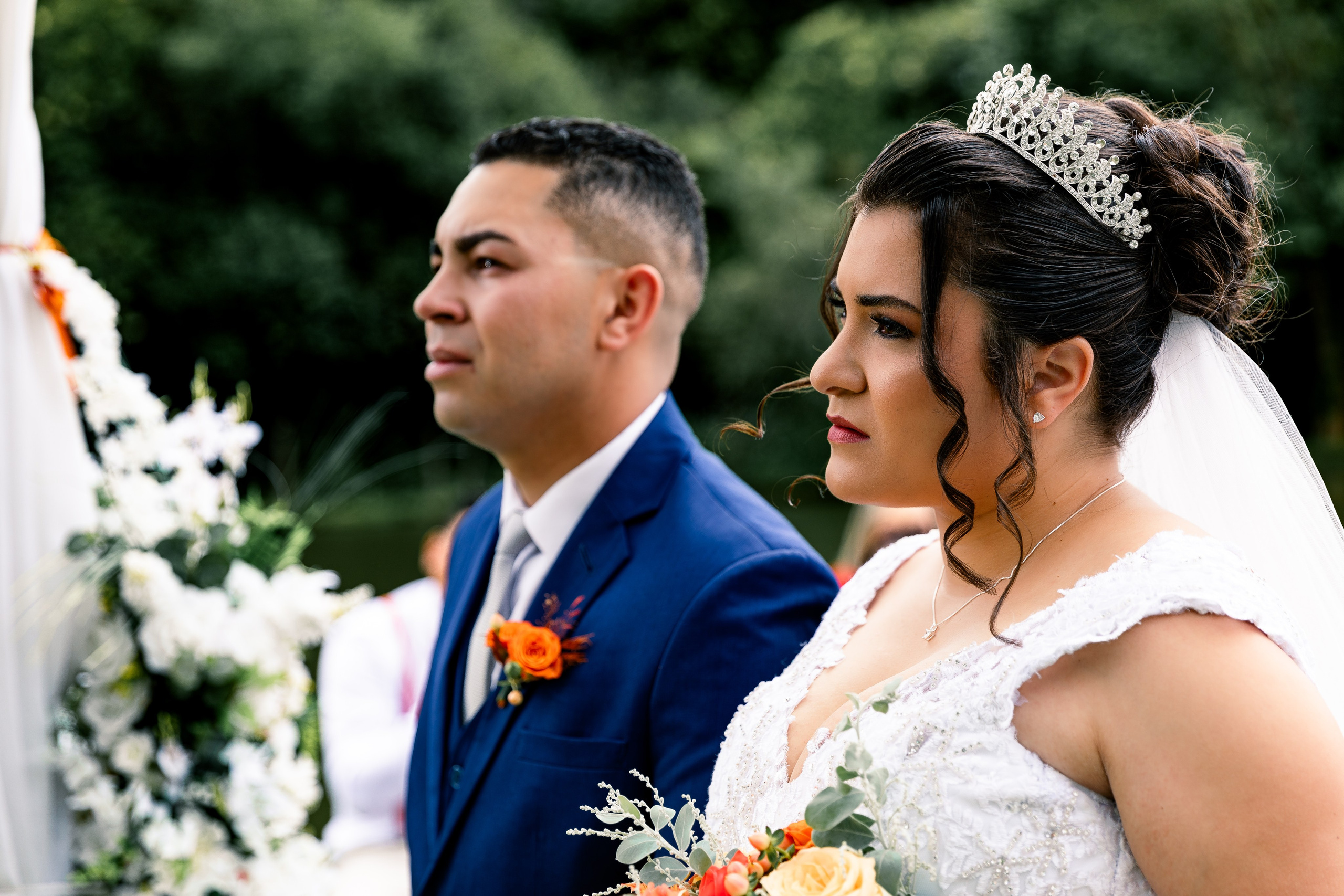 Noivos durante a cerimônia de casamento, concentrados na fala do celebrante.