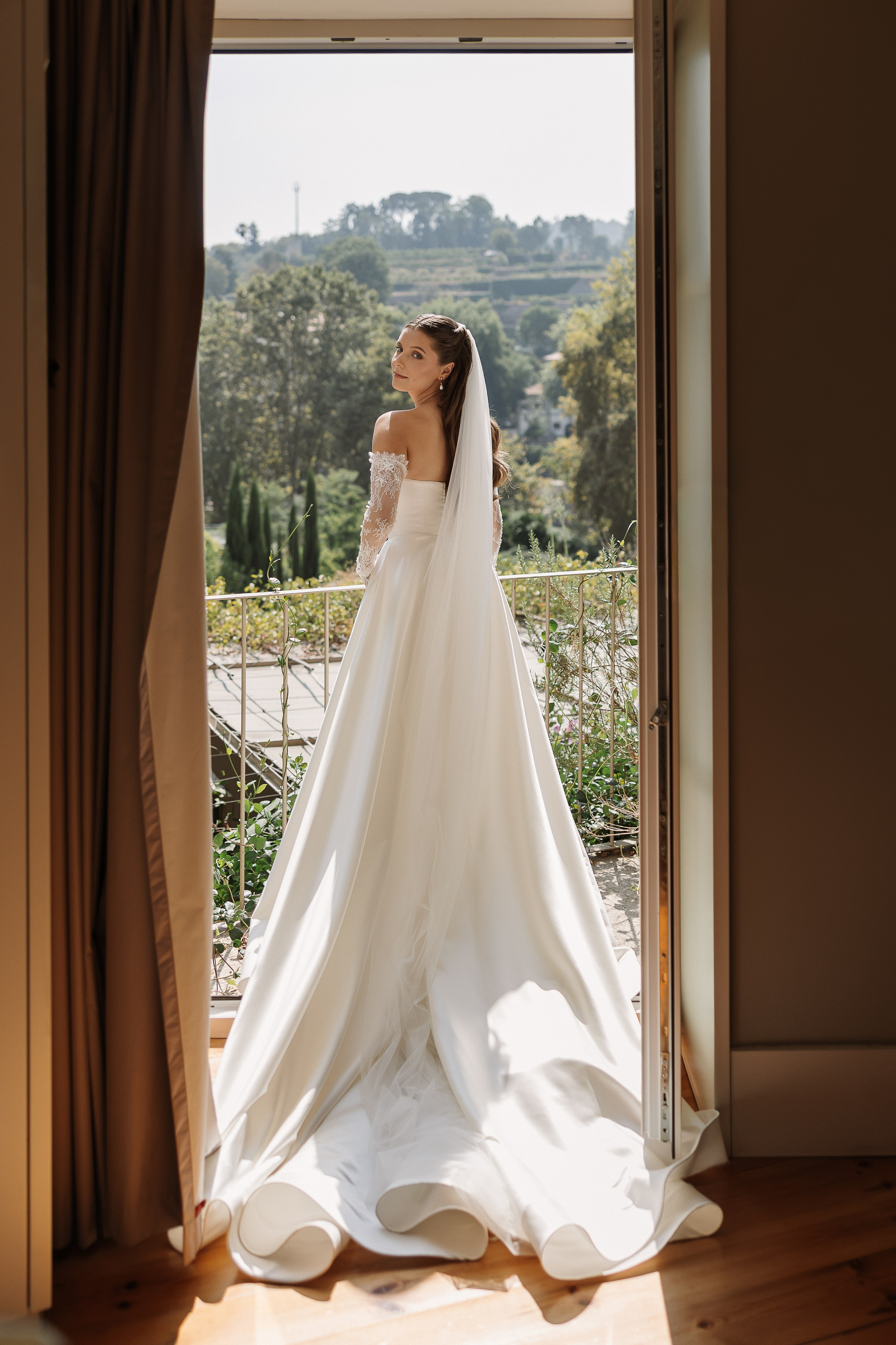 Noiva com vestido e véu junto à janela antes da cerimónia