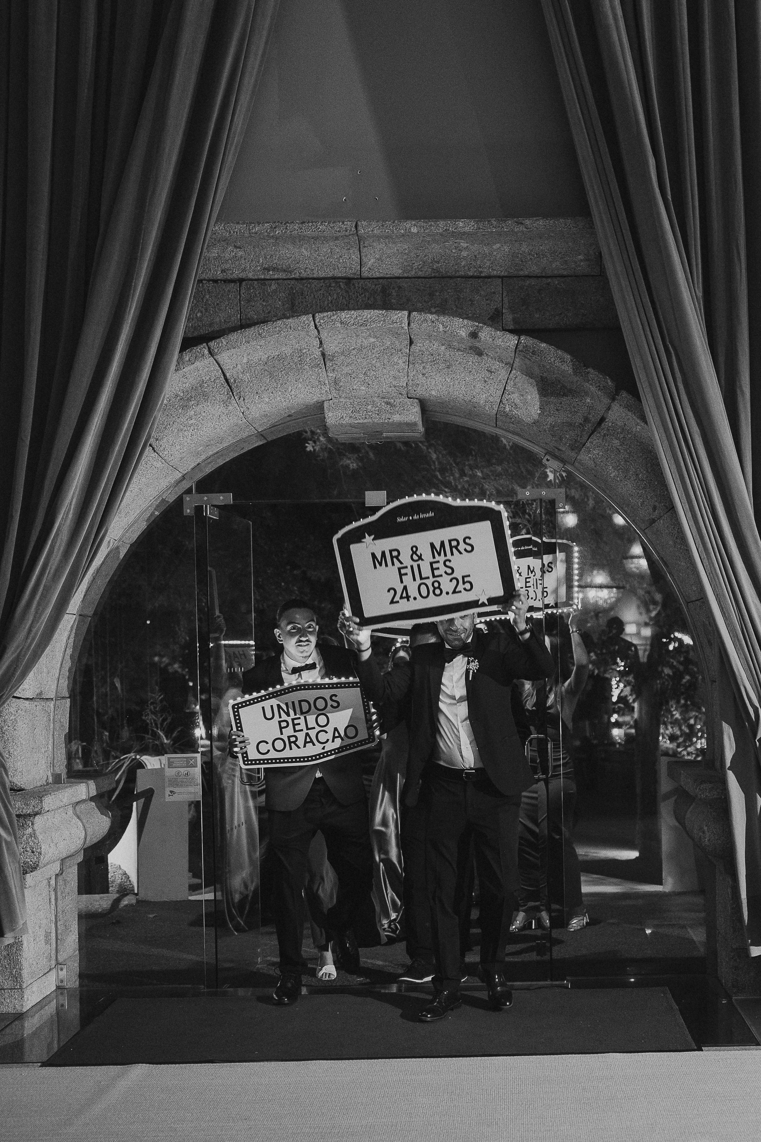Noivos e convidados com placas durante a festa em fotografia a preto e branco