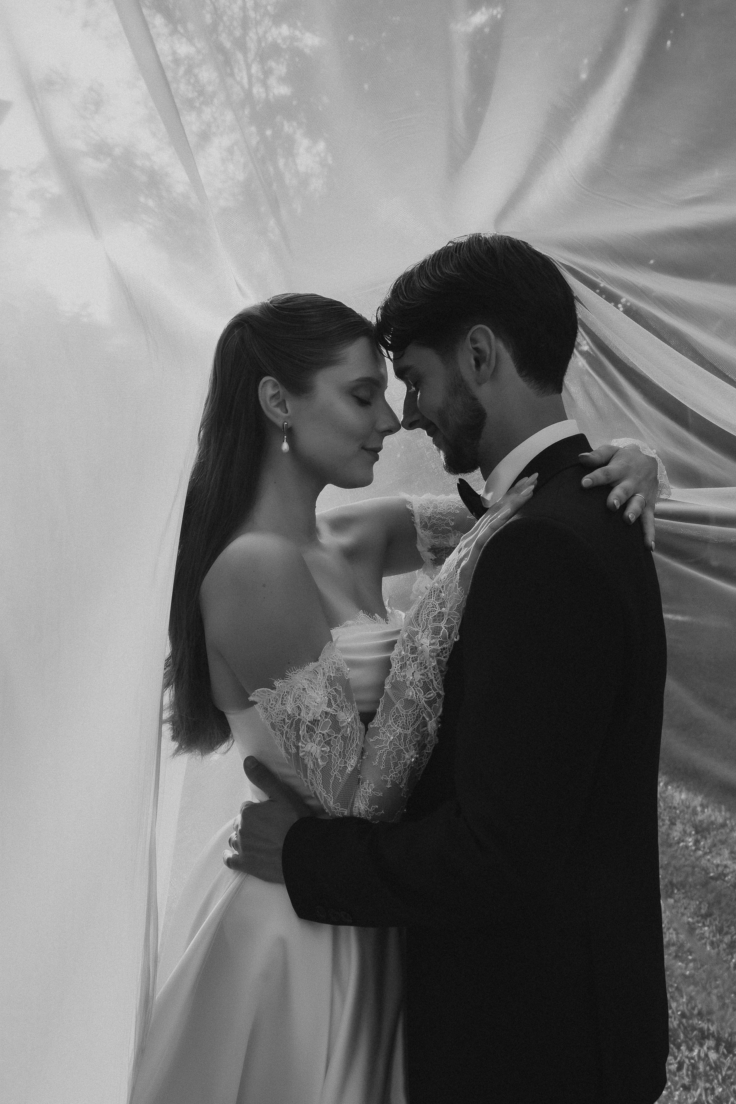 Beijo dos noivos através do véu em fotografia a preto e branco