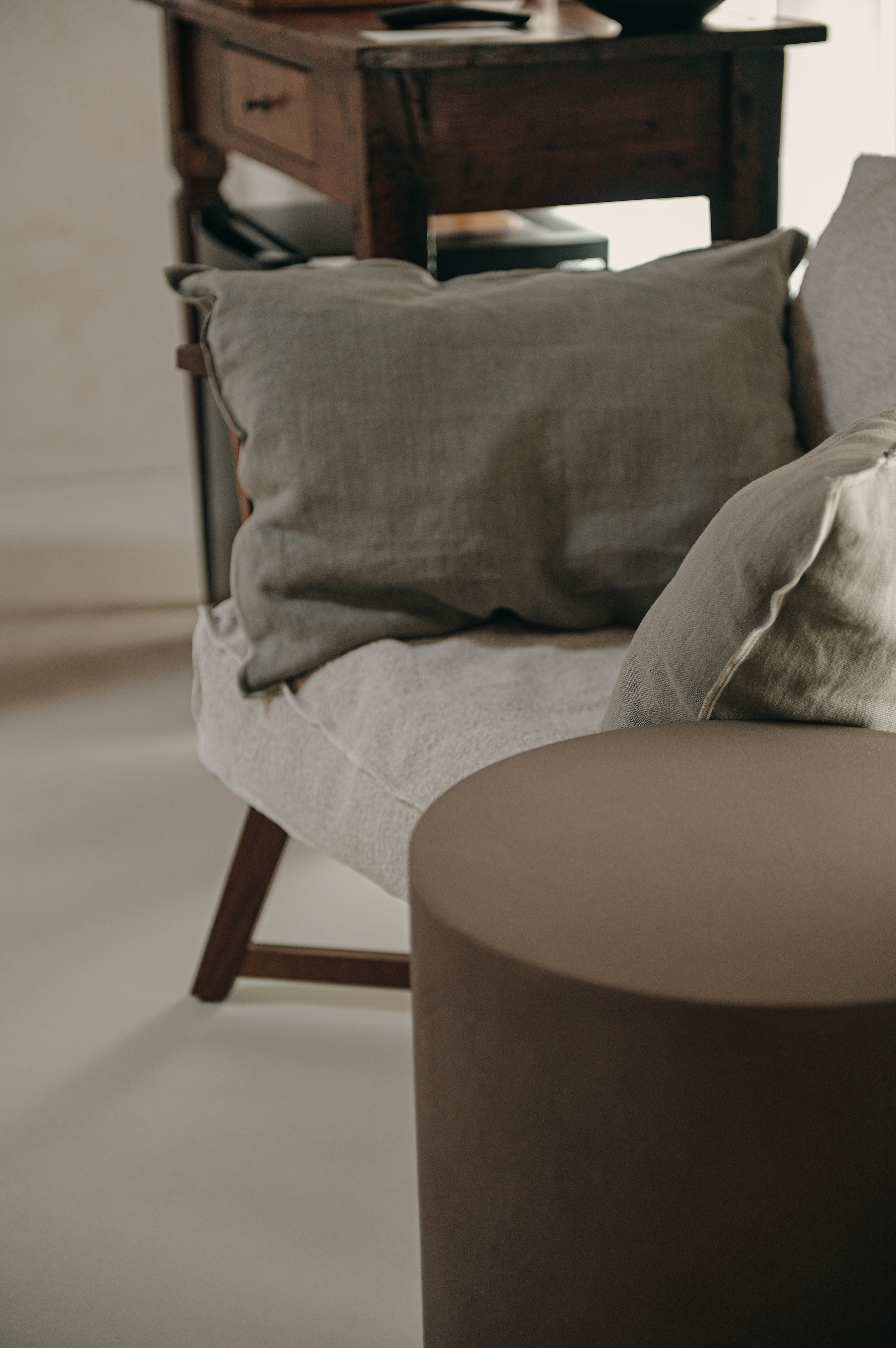 Detail of a cozy reading corner with linen cushions and wooden desk in a boutique interior in Puglia, Italy.