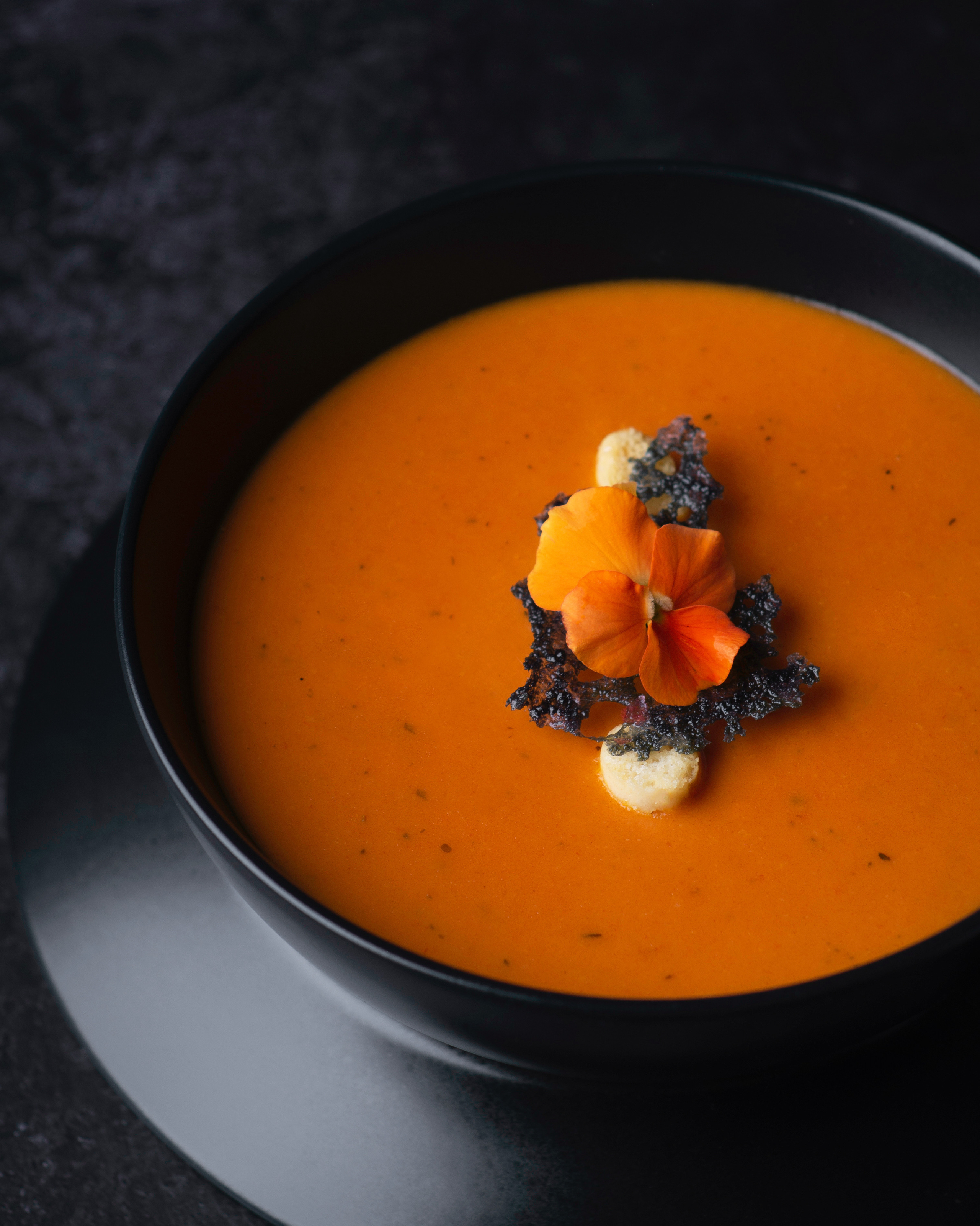 cream of tomato soup with croutons in black bowl 