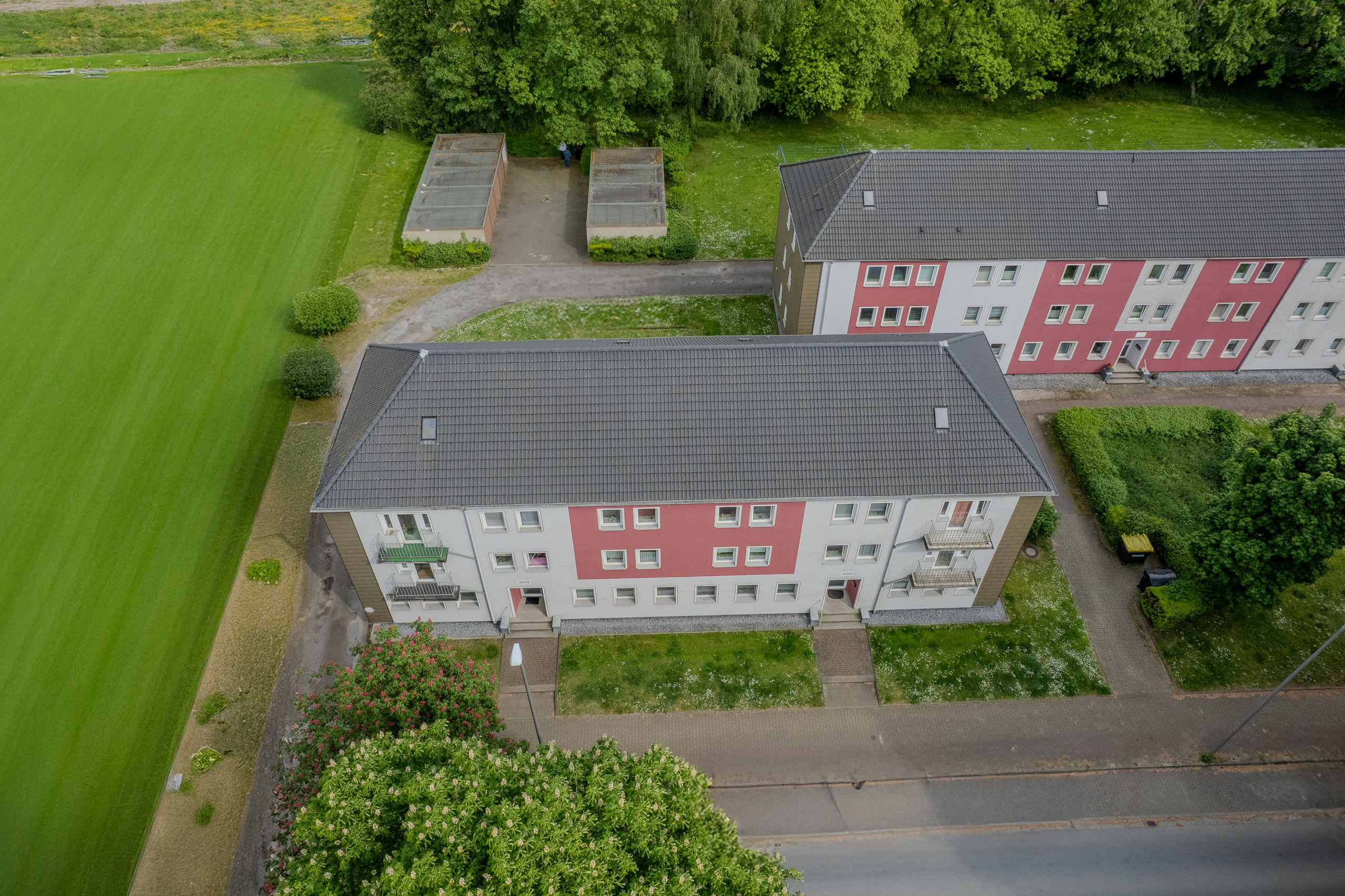 Аэрофотосъемка многоквартирного дома в HDR. Фасад, серая скатная крыша, земельный участок с зеленым газоном и подъездной дорогой. Панорамный вид с высоты, сделанный с помощью дрона.