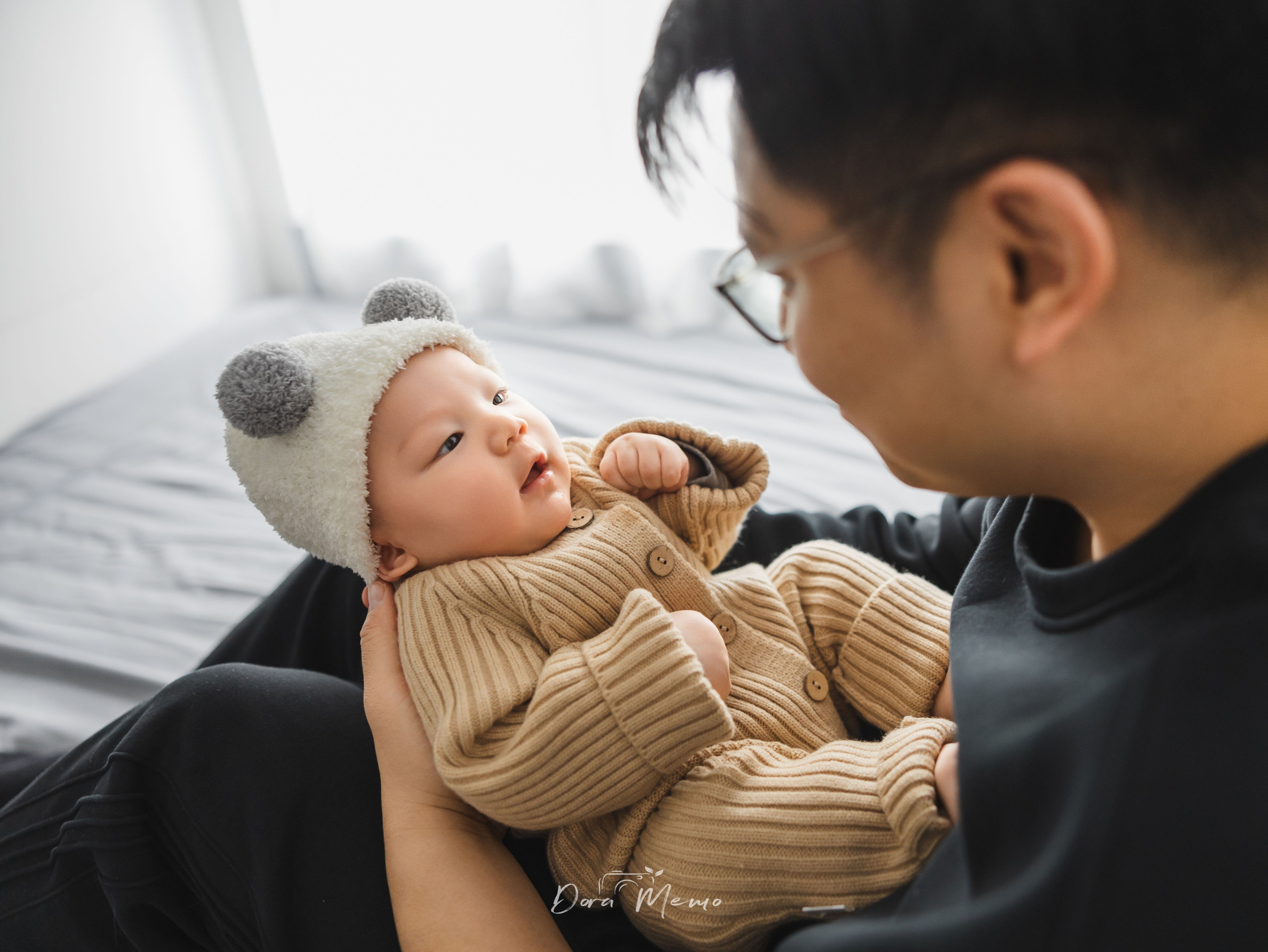 Father holding baby in beige outfit with cute bear hat, lifestyle newborn session Shanghai