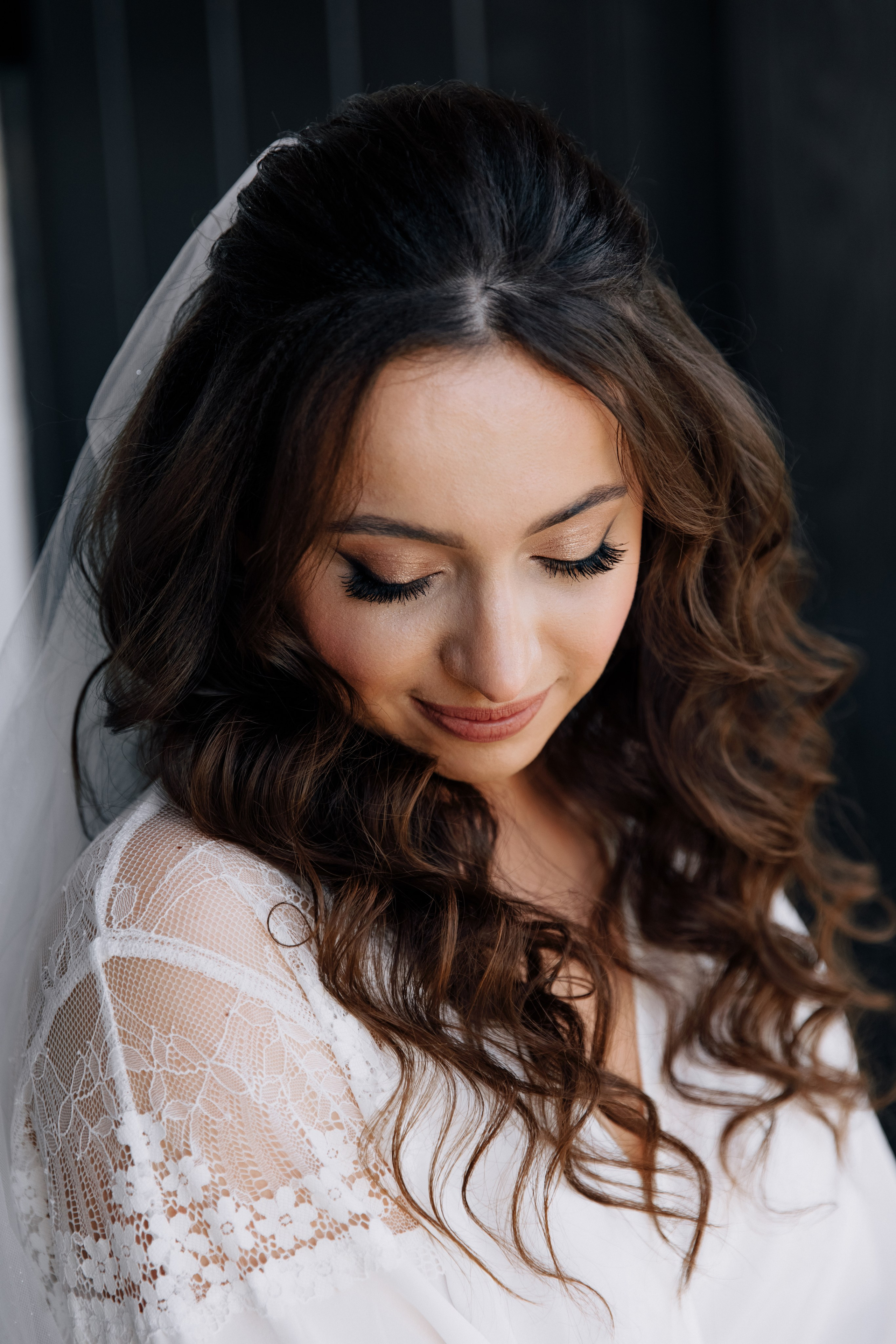 Die Braut schaut nach unten während der Hochzeitsvorbereitungen, ihr wunderschönes Make-up ist gut sichtbar.