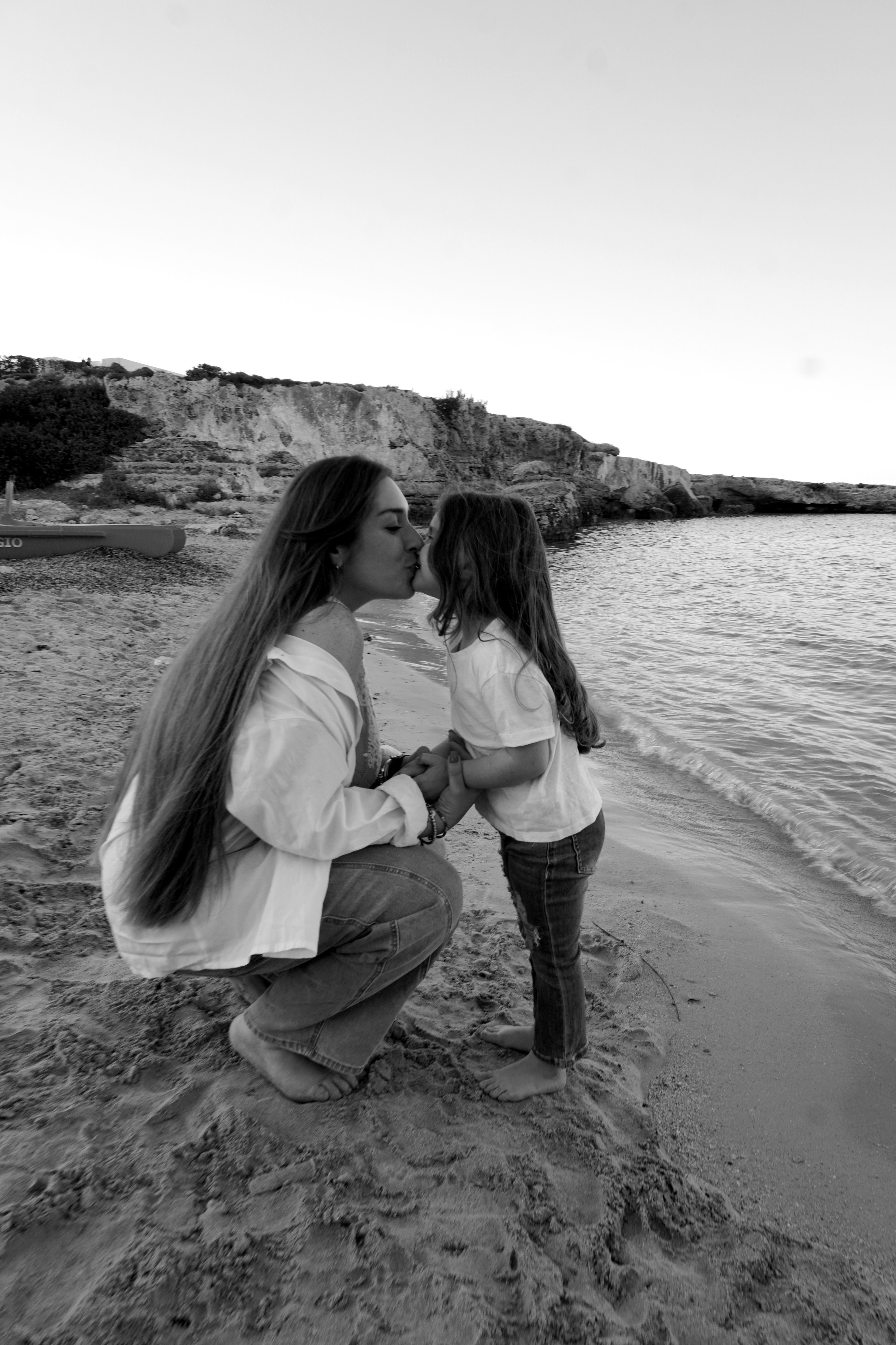 Famiglia sorridente seduta su una coperta vicino alla riva in Puglia.