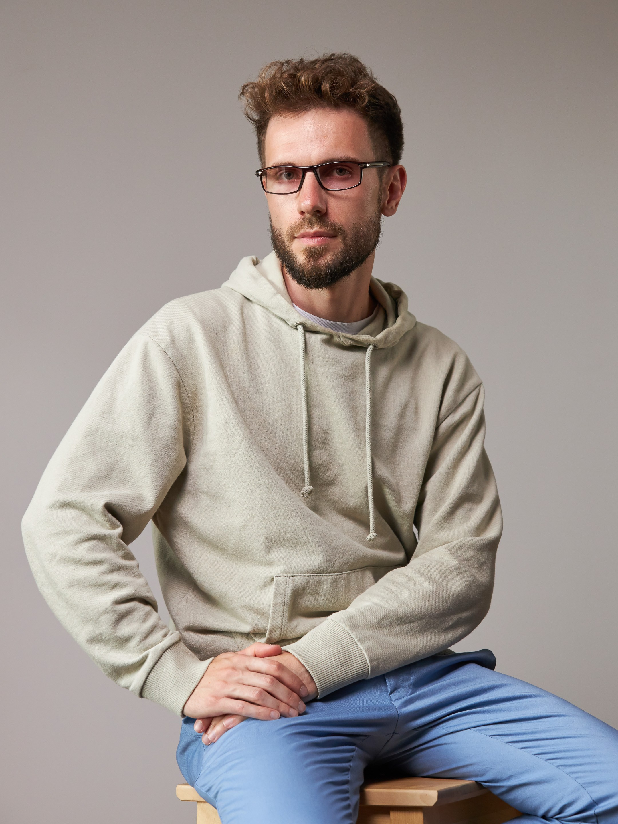 Eyewear model photoshoot - studio portrait of a young man on warm grey background - photographer Andrey Dunin